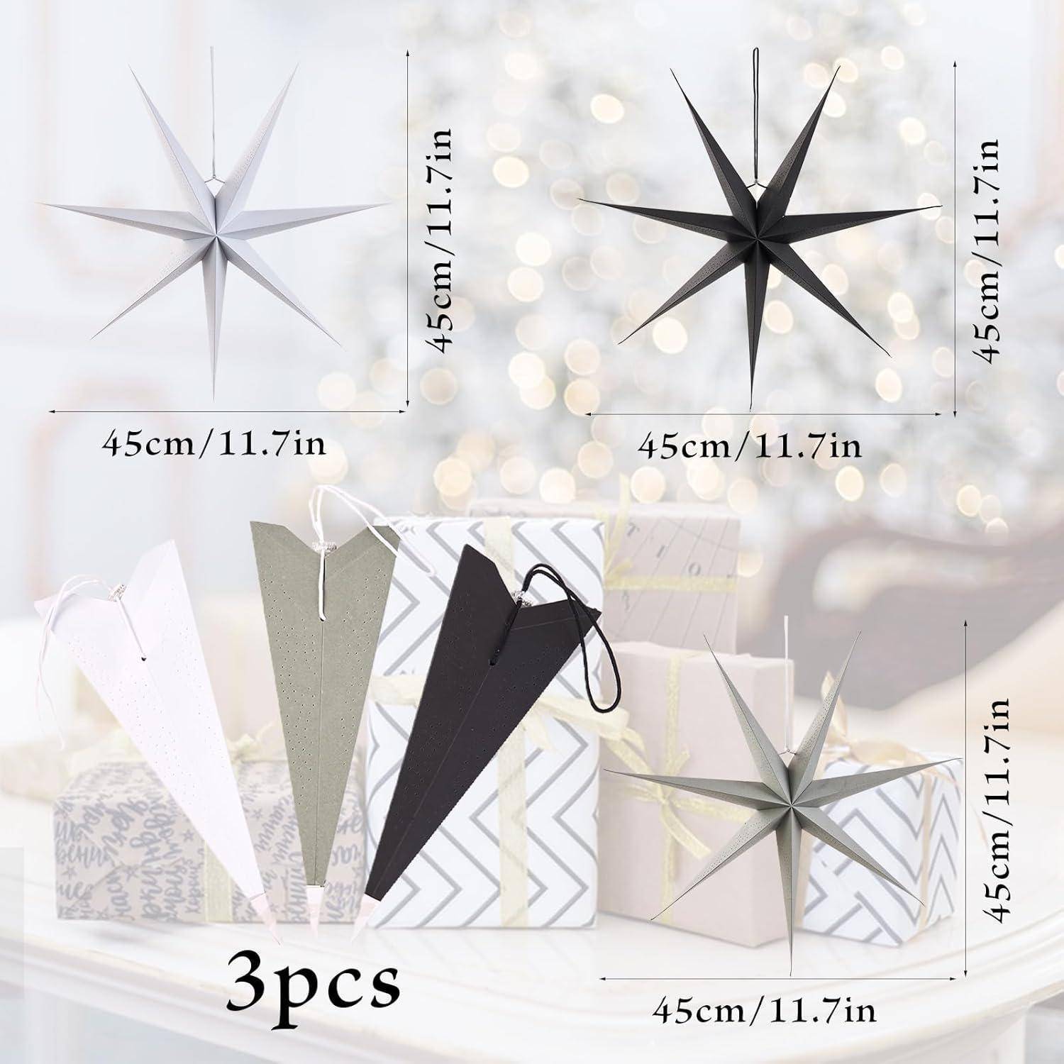 Drei Sterndekorationen, die 45 cm/11,7 Zoll messen, in Schwarz, Grau und Weiß gezeigt, mit Geschenkkartons im Hintergrund.