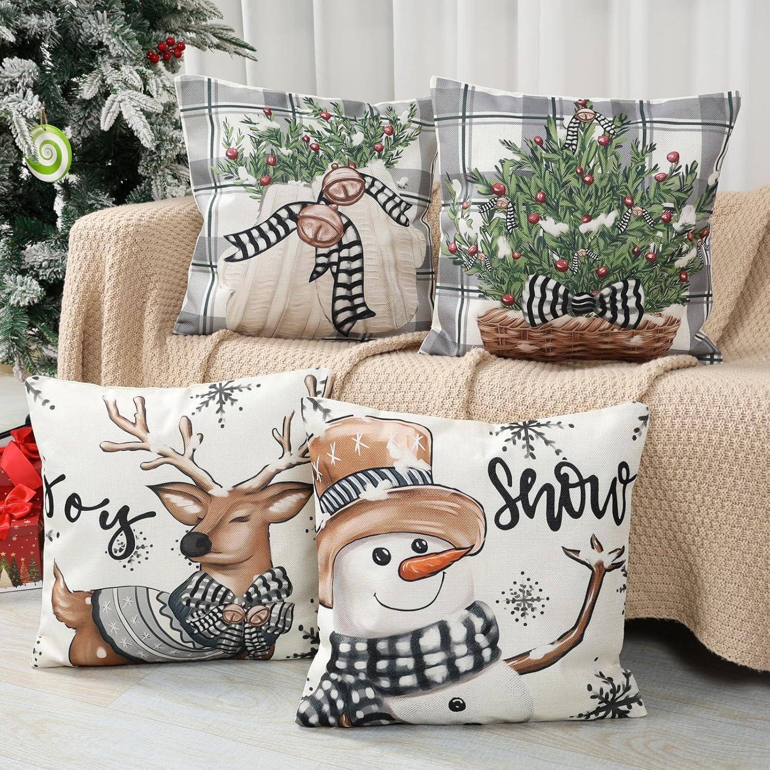 Festliche Kissenbezüge mit Weihnachtsmotiven auf einem beigen Sofa präsentieren rustikale Designs: einen Weihnachtsbaum, einen Schneemann, ein Rentier und weihnachtliche Grüße.