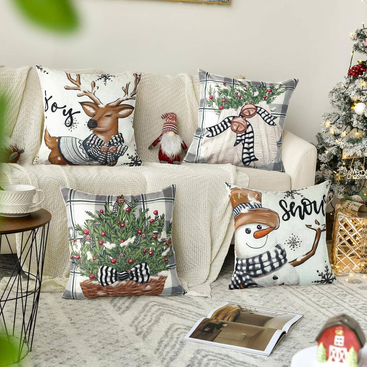 Ein gemütliches Wohnzimmer mit weihnachtlich gestalteten Kissen, die Rentiere, Christbaumschmuck und Schneemann-Motive zeigen, neben einem dekorativen Weihnachtsbaum.