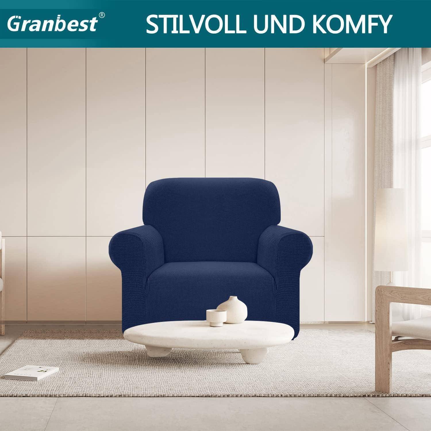 Ein gemütliches Wohnzimmer mit einem blauen Sessel, auf einem niedrigen weißen Couchtisch steht eine Tasse, darunter hängt ein Schild in Petrolfarben mit der Aufschrift 'STILVOLL UND KOMFY'.