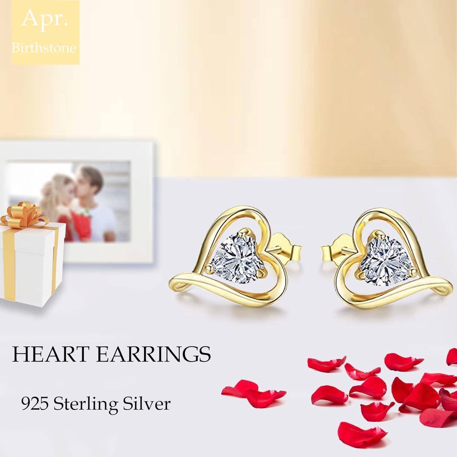 Goldene herzförmige Ohrringe mit klaren Steinen werden präsentiert. Text lautet: 'Apr. Geburtsstein, Herz-Ohrringe, 925 Sterling Silber' mit Rosenblütenblättern.