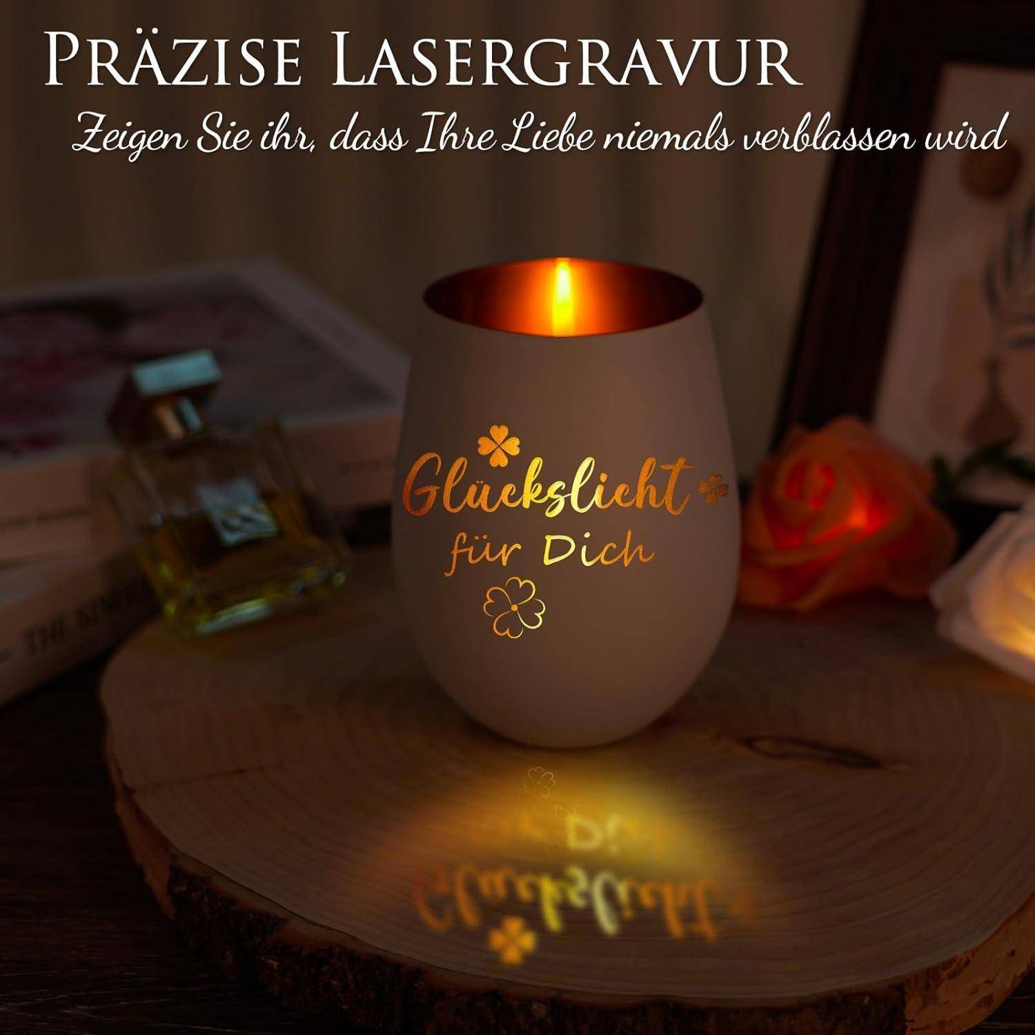 Ein leuchtendes Kerzenhalter mit der Gravur 'Glückslicht für Dich', auf einer Holzunterlage platziert. Umgeben von einer Parfümflasche und einer Rose.