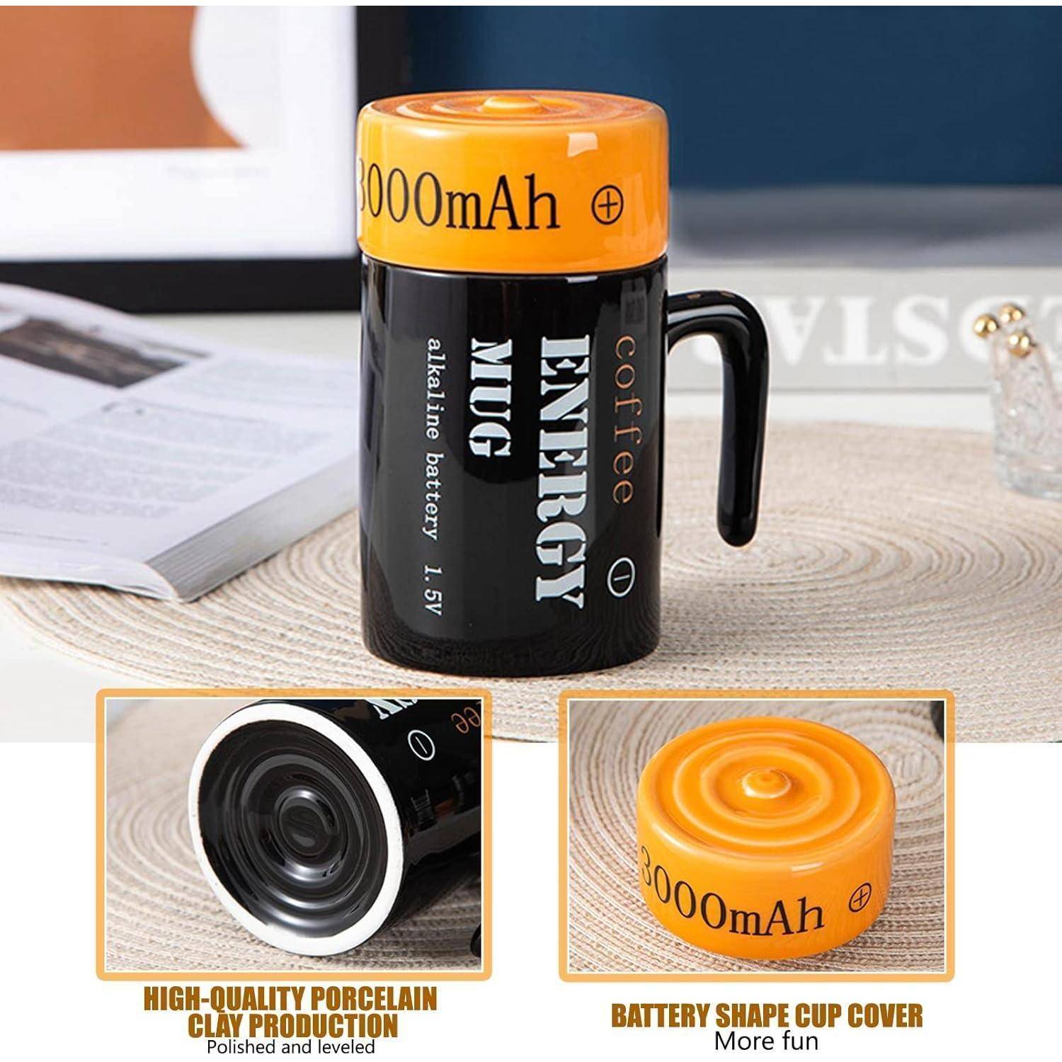 Energiemug in Batterieform mit der Aufschrift '8000mAh' auf einem orangefarbenen Deckel, auf einem Tisch platziert; betont das einzigartige Design.