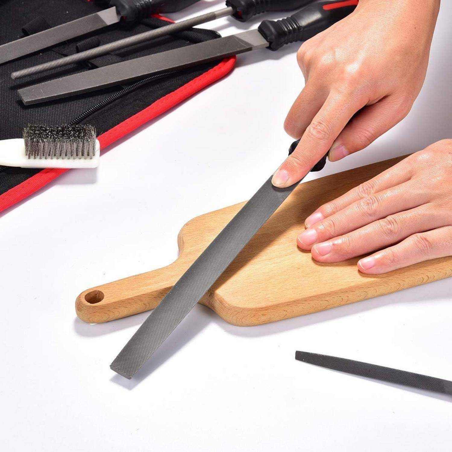 Hände, die ein Messer auf einem Stein über einem Holzschneidebrett schärfen, umgeben von Schleifwerkzeugen, einschließlich einer Bürste und anderer Zubehörteile.