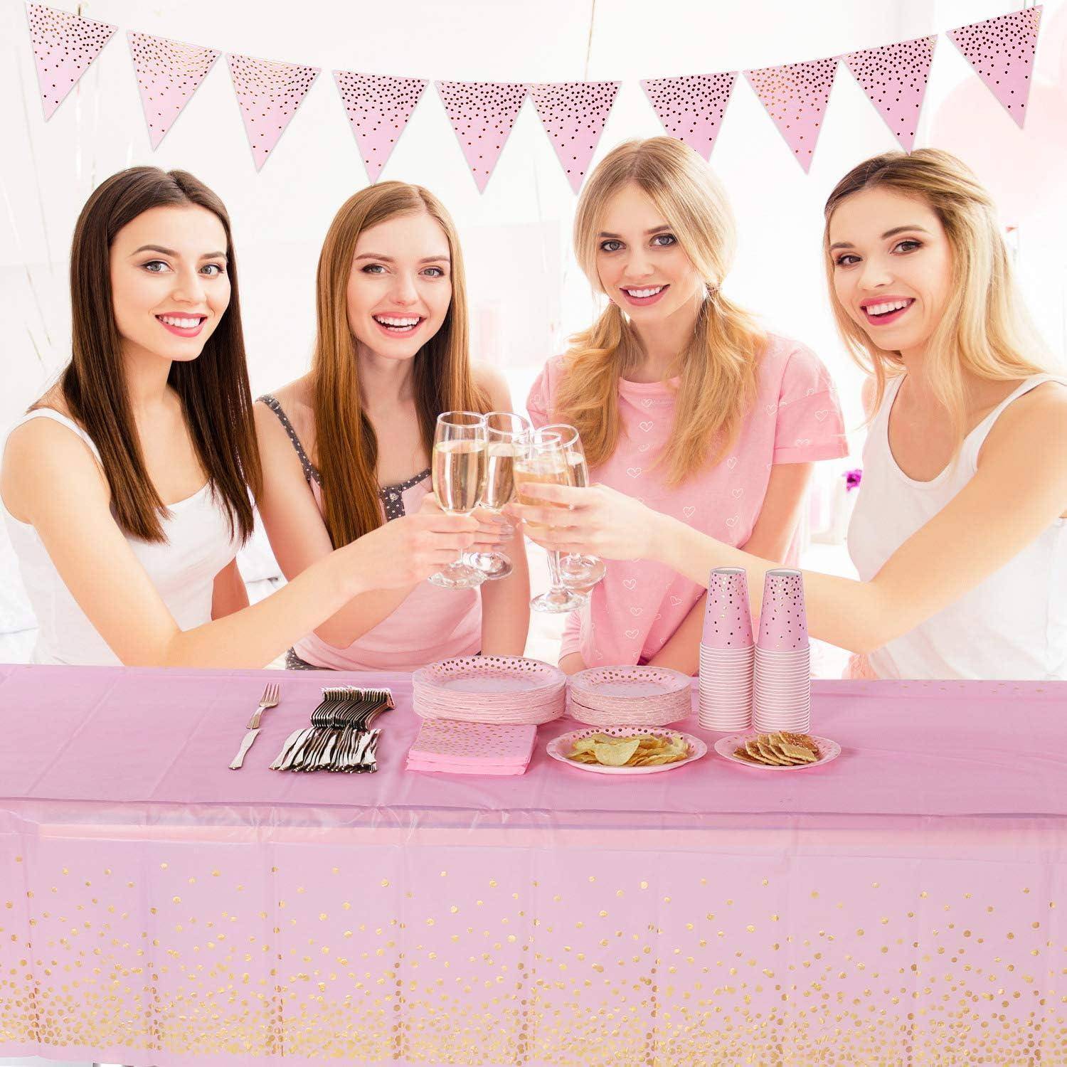 Vier Frauen feiern an einem Tisch mit rosa Dekorationen und stoßen mit Champagnergläsern an, während über ihnen eine rosa Wimpelgirlande hängt.