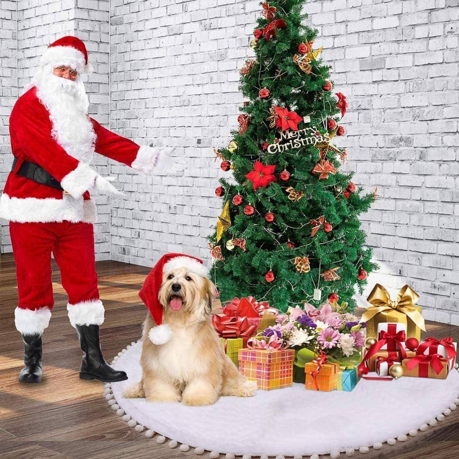 Eine Person, die als Weihnachtsmann verkleidet ist, steht neben einem geschmückten Weihnachtsbaum mit einem Schild, auf dem 