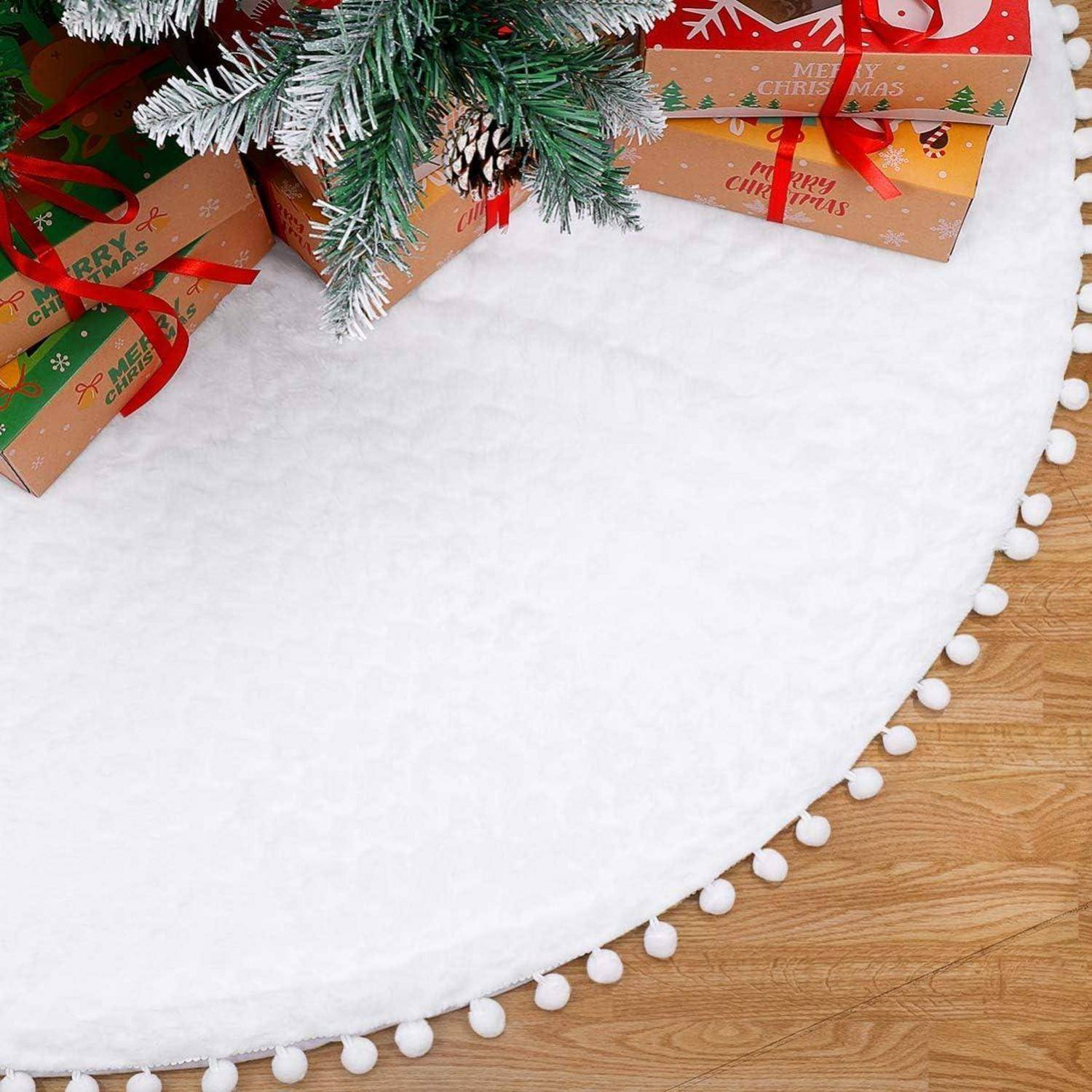 Weihnachtsgeschenke in rot und gold verpackt sitzen unter einem geschmückten Baum mit weißem Pompom-Rock und erschaffen eine festliche Atmosphäre.