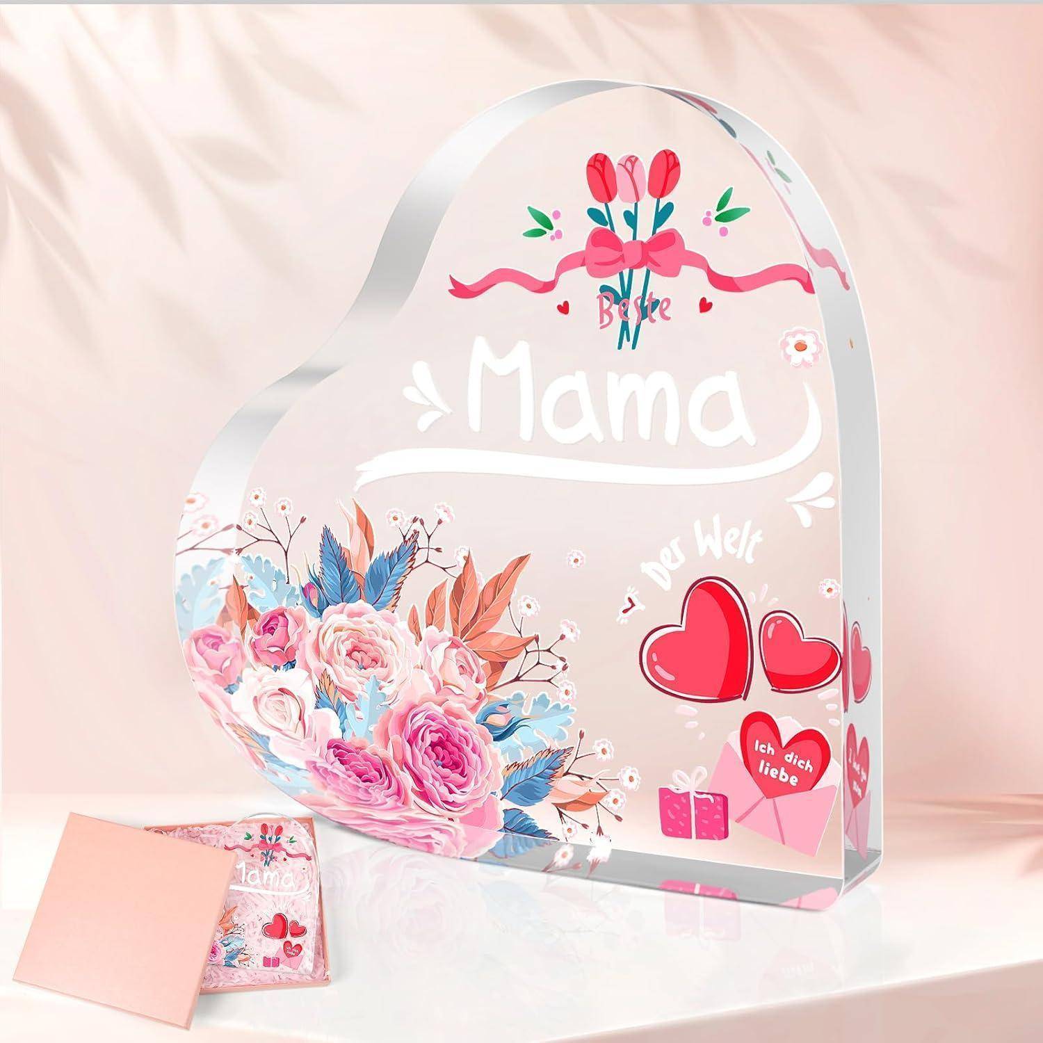 Eine herzförmige Acrylplakette mit der Aufschrift 'Mama' und einem floralen Design mit Rosen und Tulpen, begleitet von einem kleinen rosa Umschlag und einer Karte.