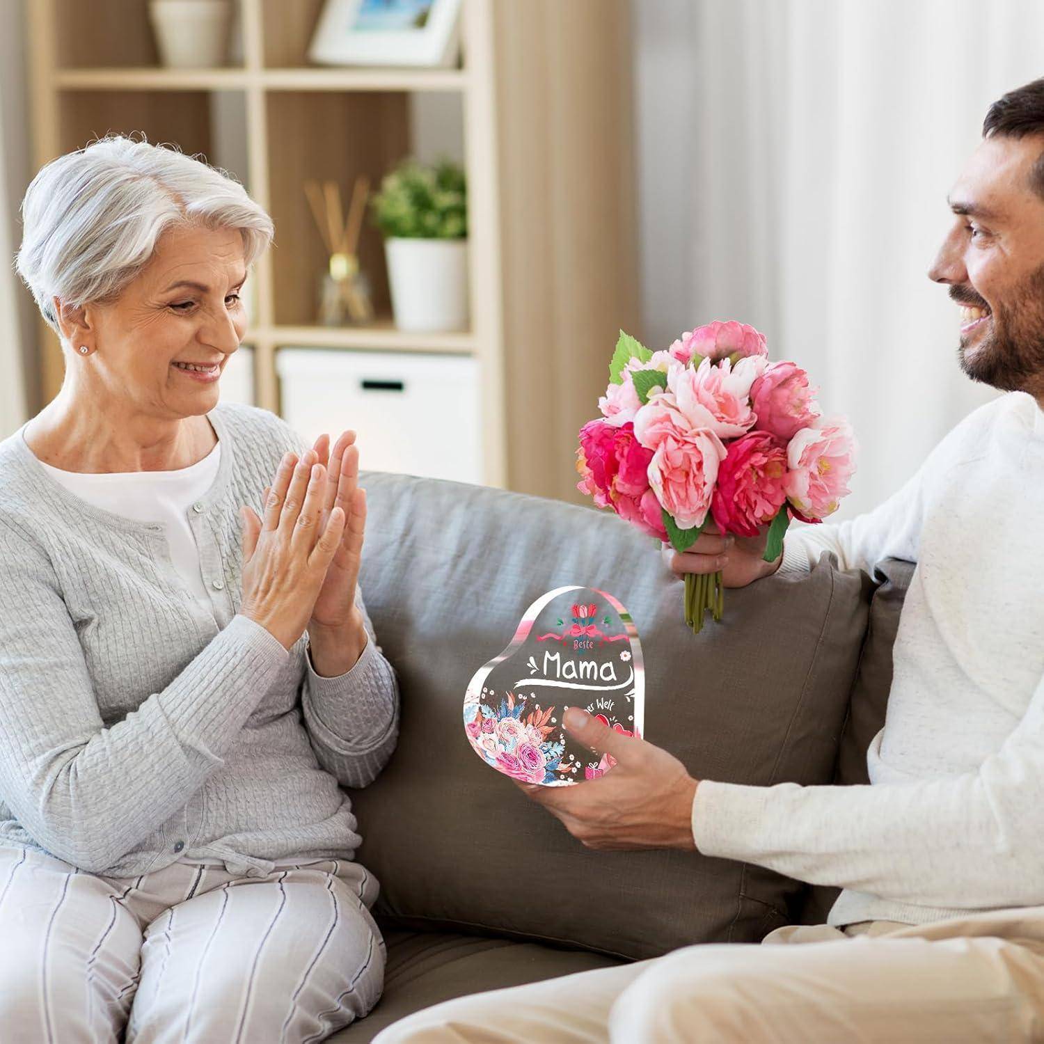Eine ältere Frau lächelt, während sie ein herzförmiges Geschenk mit der Aufschrift 