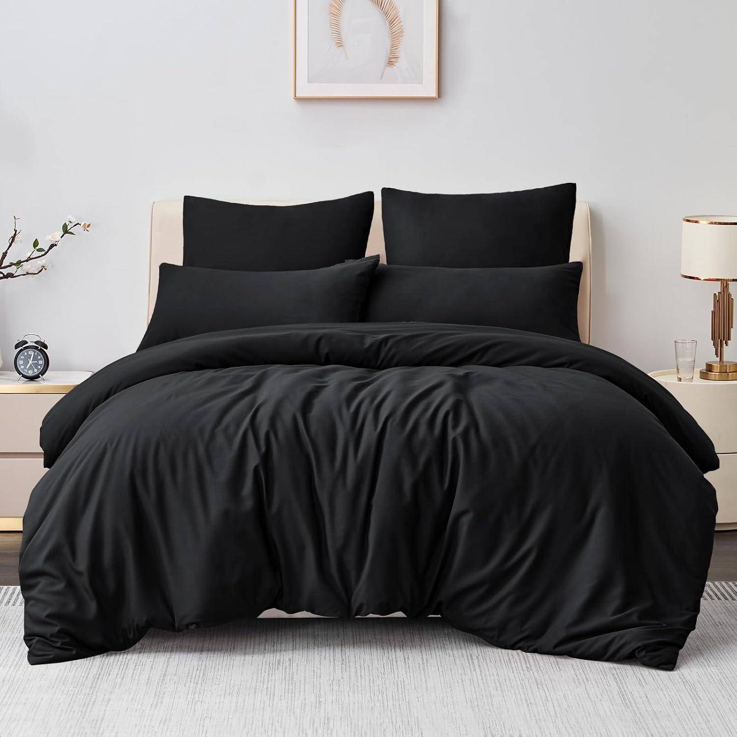 Schwarzes Bettwäsche-Set auf einem ordentlich gemachten Bett mit zwei Kissen, vor einer neutralen Wand mit minimaler Dekoration und einem kleinen Nachttisch.