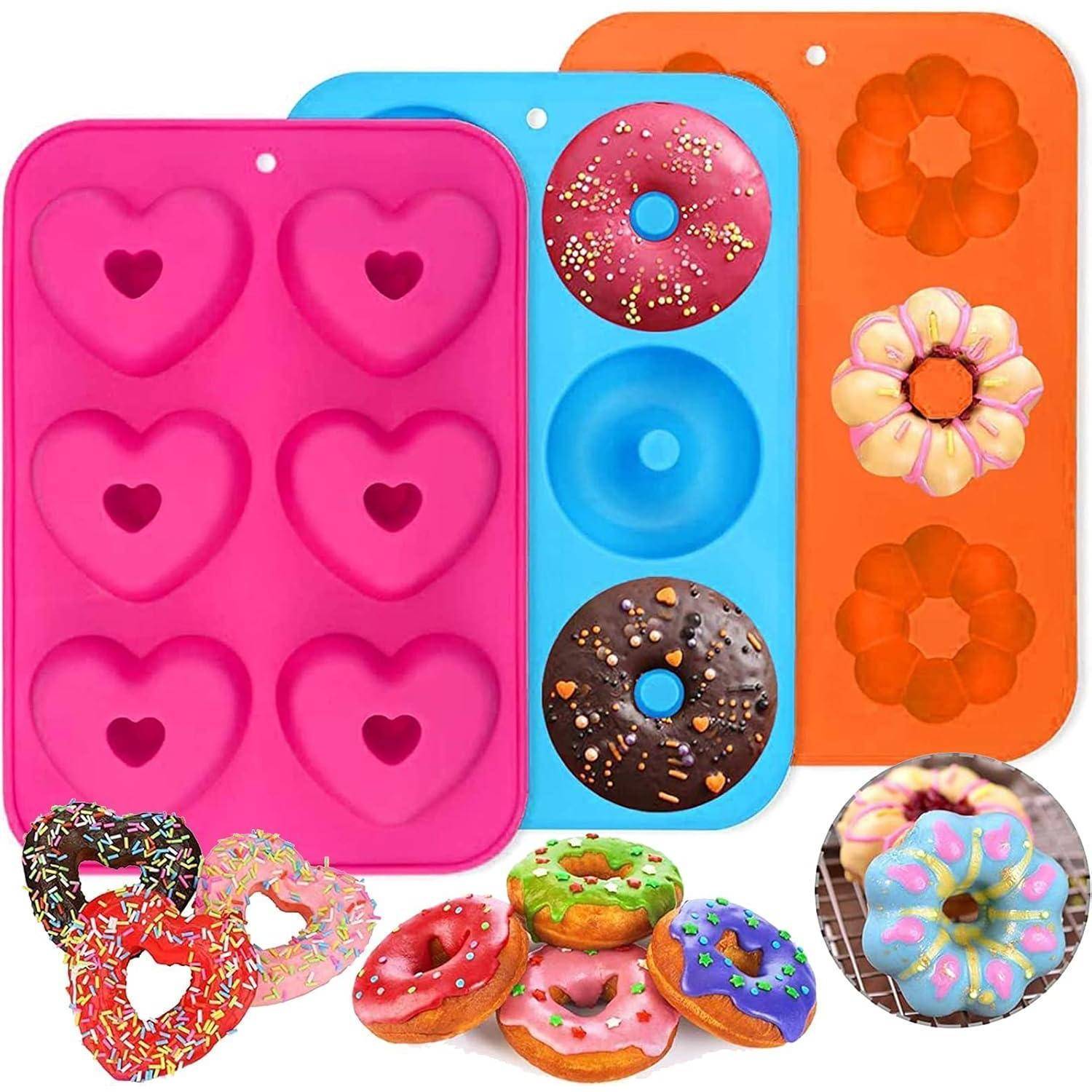 Drei Silikonbackformen: rosa Herzen, blaue Donuts, orangefarbene Blumen. Beispielhafte bunte Donuts und Streuselen sind abgebildet.