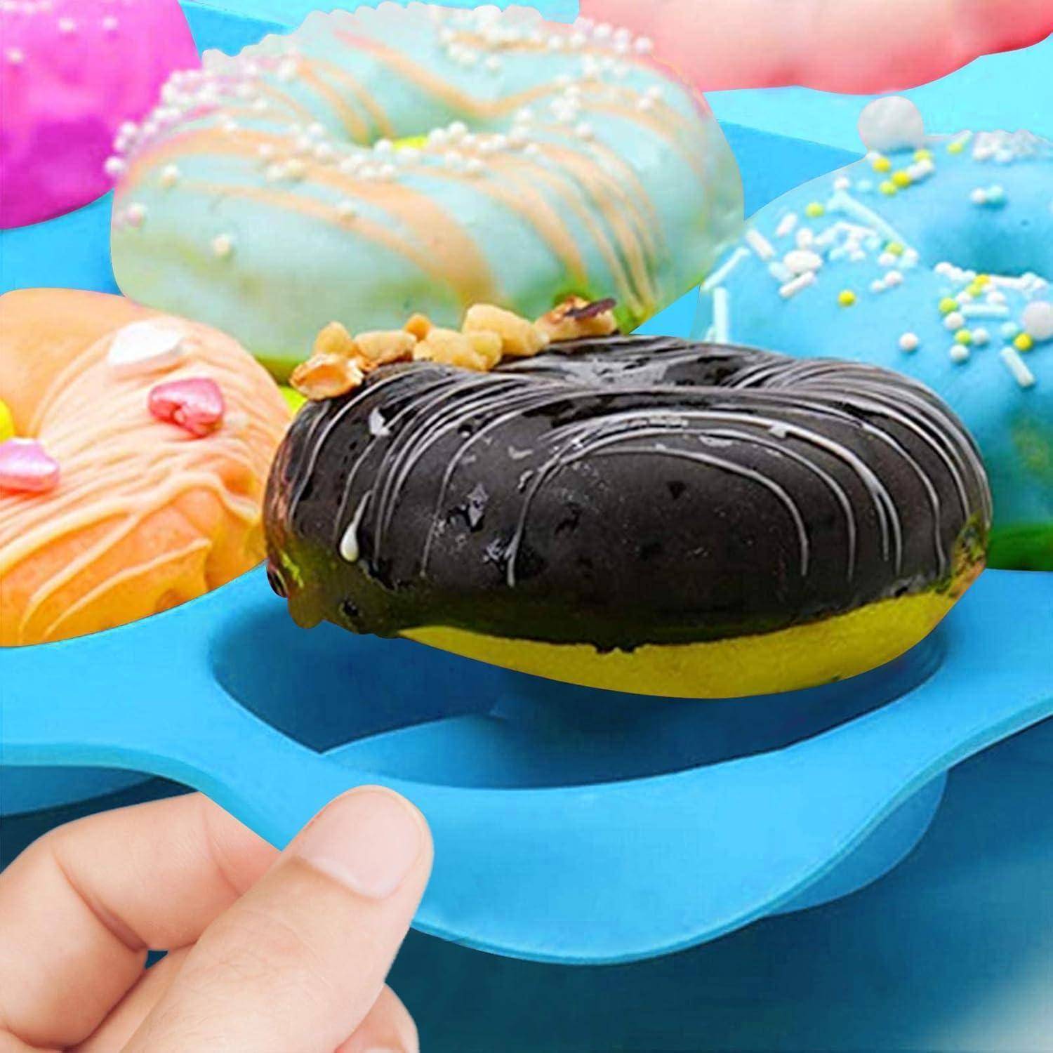 Eine Hand hält ein blaues Tablett mit bunten, verzierten Donuts. Die Donuts haben Schokoladenglasur, Streusel und Nüsse und zeigen eine große Vielfalt.