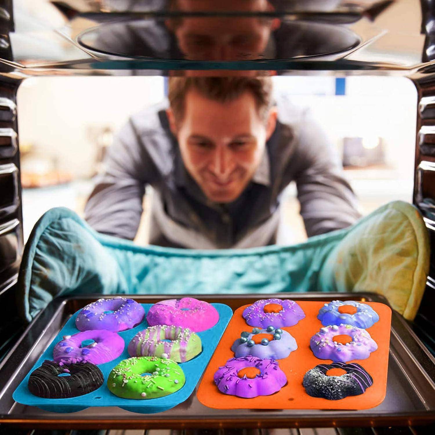Ein Mann blickt erwartungsvoll in einen Ofen und beobachtet, wie bunte Donuts auf einem Backblech backen.