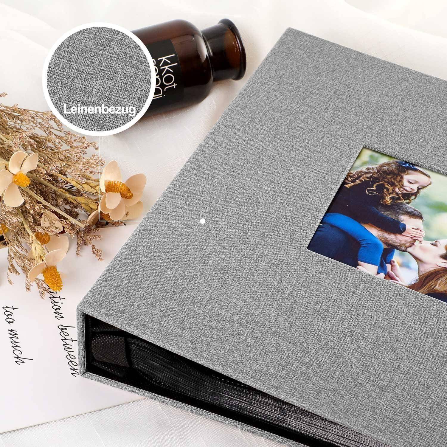 Ein graues Leinenalbum mit einem Familienfoto auf dem Einband liegt neben getrockneten Blumen und einer kleinen Flasche auf einer weißen Oberfläche.