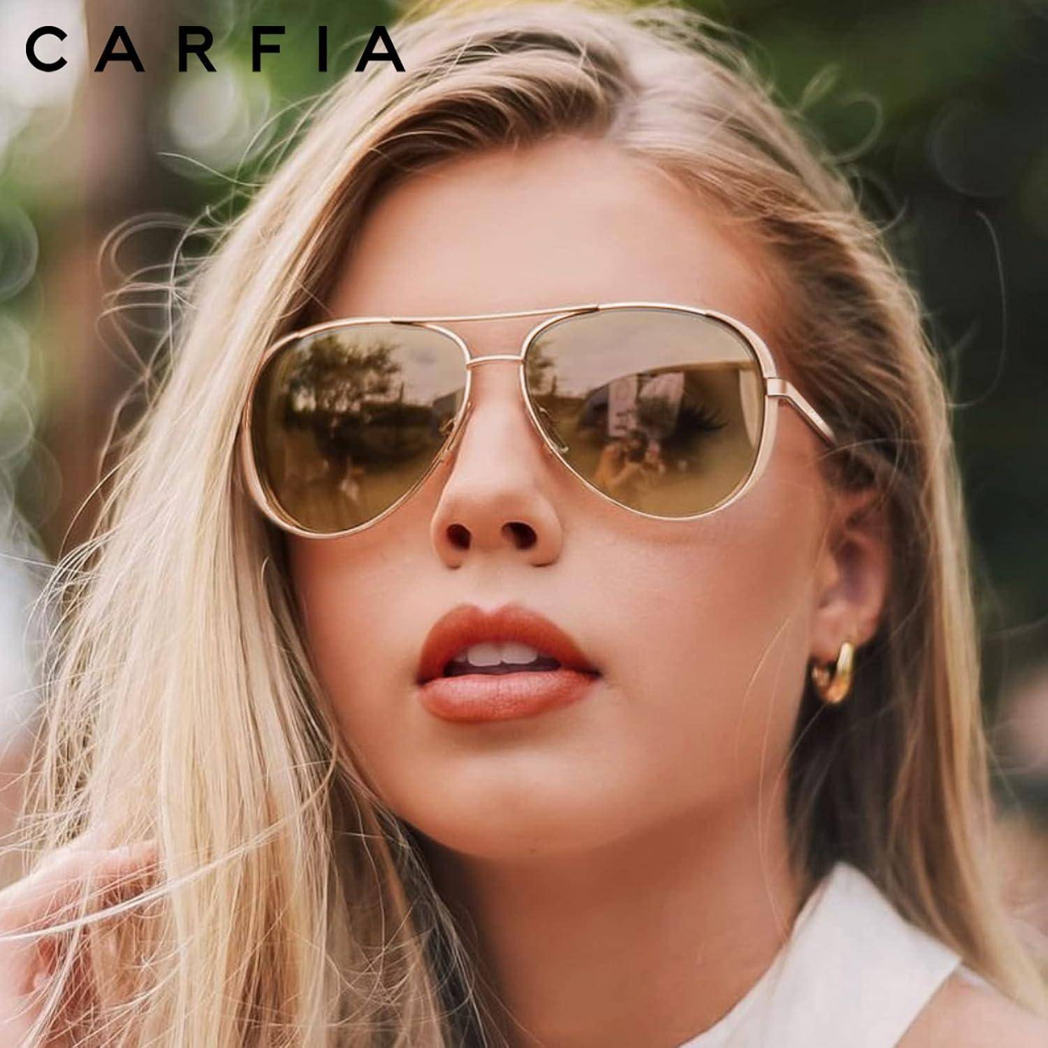Eine Person mit langen blonden Haaren trägt große Sonnenbrille und goldene Creolen und blickt direkt in die Kamera in einer Außenumgebung.