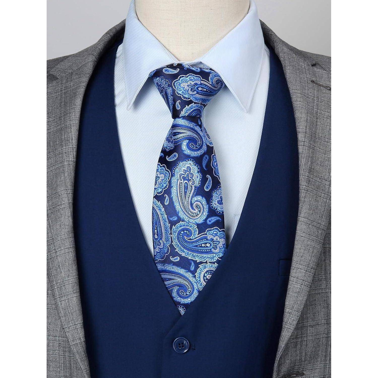 Eine Nahaufnahme einer Person, die eine blaue Paisley-Krawatte, ein hellblaues Hemd, eine marineblaue Weste und ein graues Sakko trägt und dabei formelle Kleidung zur Schau stellt.