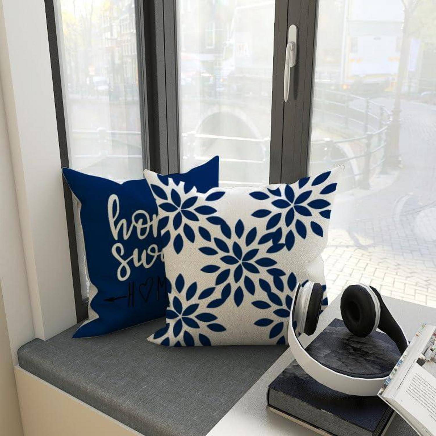 Ein gemütlicher Fenstersitz mit zwei dekorativen Kissen, eines mit einem blauen und weißen Blumenmuster und das andere mit dem Text 