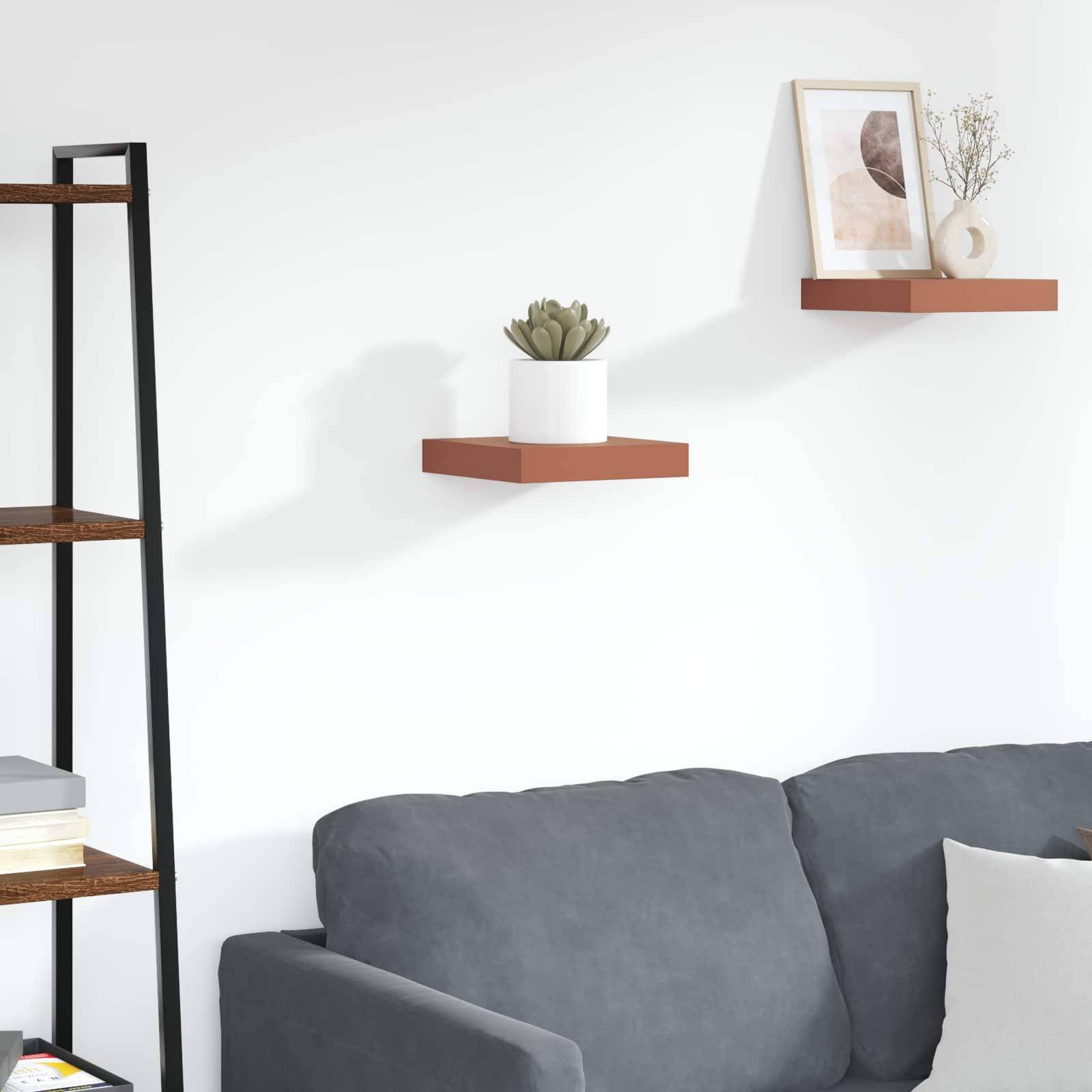 Ein minimalistisches Wohnzimmer zeigt ein graues Sofa, ein wandmontiertes Regal mit einer Topfpflanze und einem gerahmten abstrakten Kunstwerk darüber.