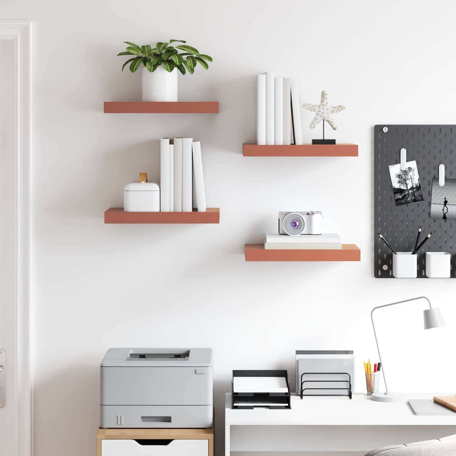 Ein aufgeräumtes Home Office mit einem Drucker auf einem Schrank, einem Schreibtisch mit Büchern und Schreibwaren sowie Regalen an der Wand, auf denen Pflanzen und Dekoartikel stehen.