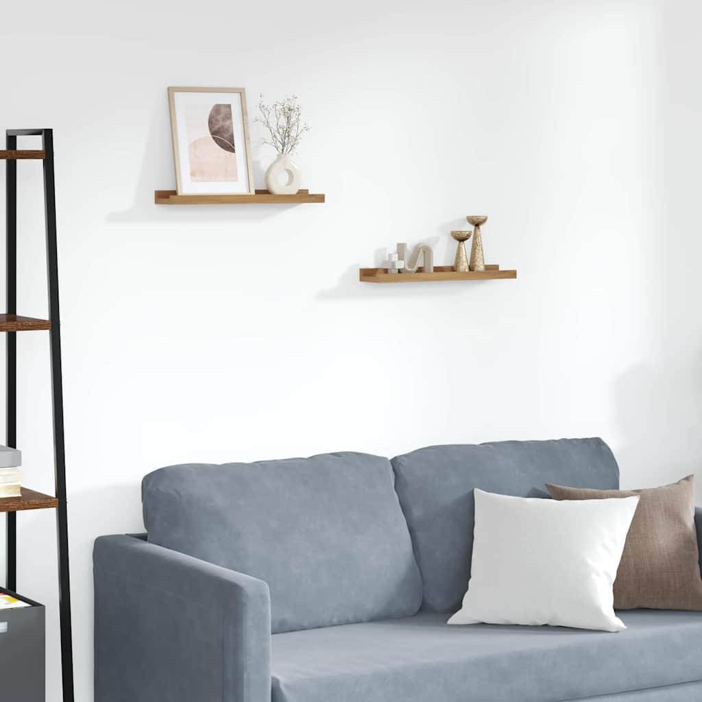 Ein gemütliches Wohnzimmer zeigt ein blaues Sofa mit weißen und beigen Kissen, zwei minimalistische Holzregale mit Kunst, einer Vase und einer Kerze.