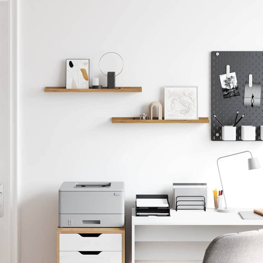 Ein aufgeräumter, moderner Bürobereich mit zwei Holzregalen, die Dekoartikel tragen, und einer schwarzen Lochplattenrückwand mit Fotos. Darunter ein Drucker, Bücher und eine Lampe auf einem Schreibtisch.