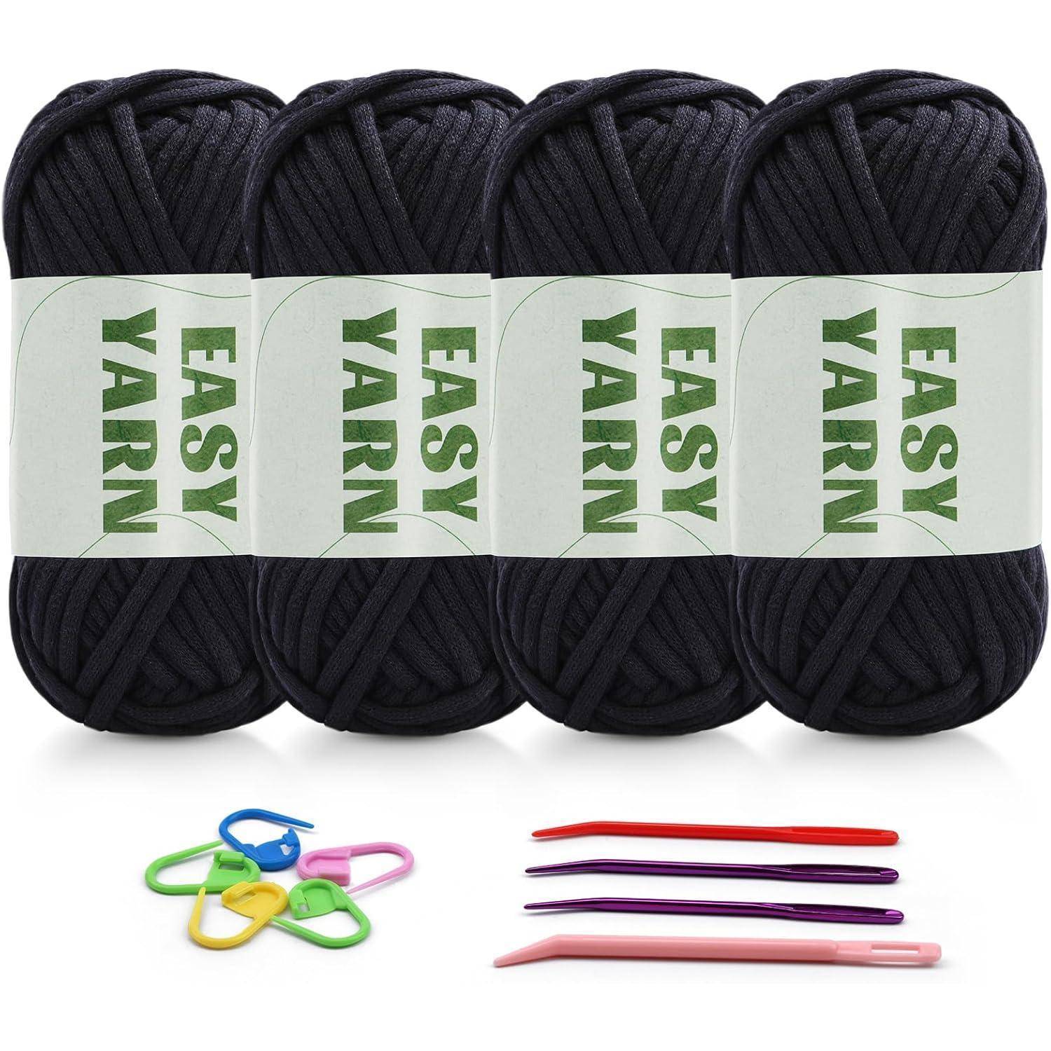 Vier Knäuel schwarzes Easy Yarn mit Etiketten, drei Maschenmarkierer und vier Häkelnadeln in verschiedenen Farben. Ideal für Strickprojekte.
