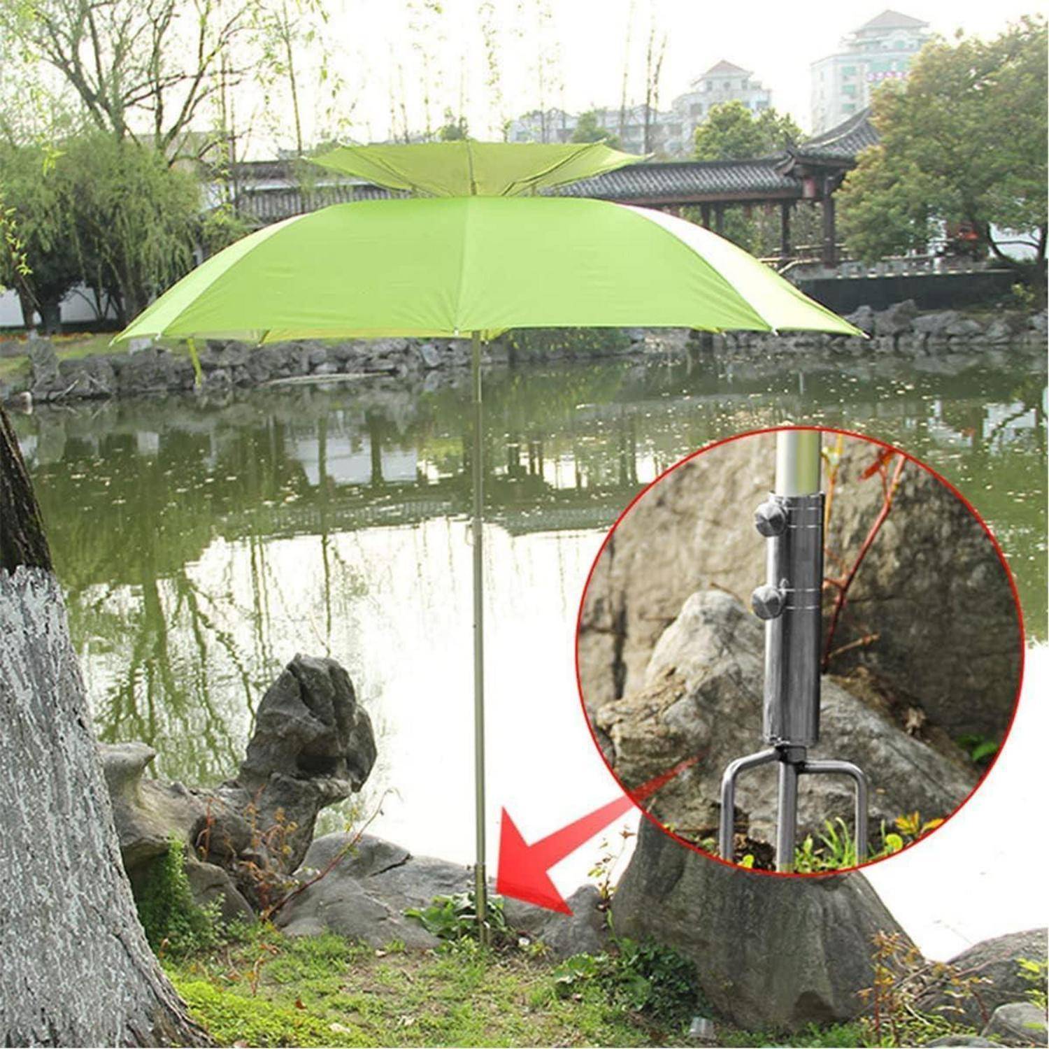Ein grüner Regenschirm steht an einem Teich in einem Park. Die Detailaufnahme zeigt die Basis des Schirms, die im Boden befestigt ist.