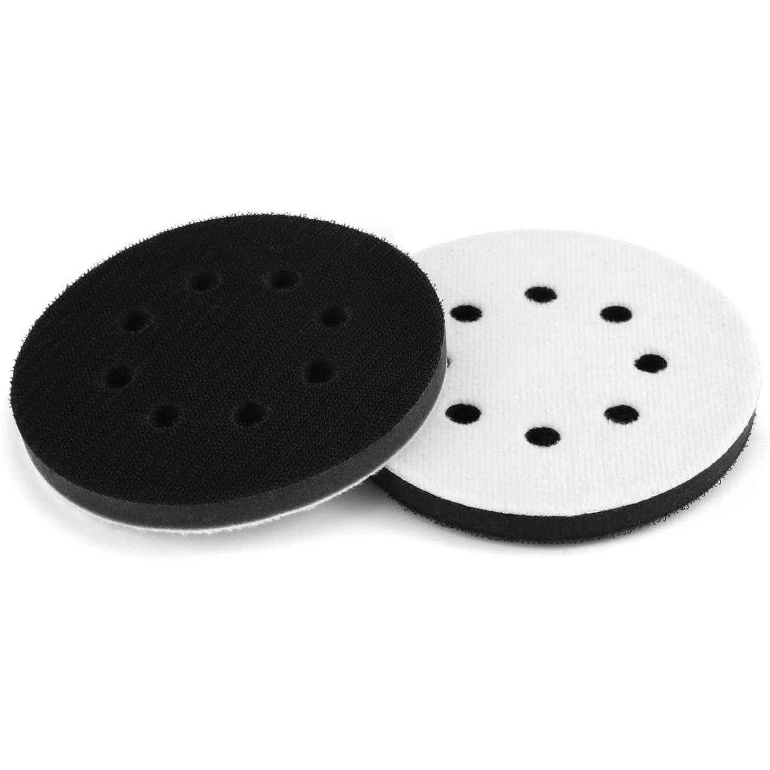 Zwei runde Schleifpads, einer schwarz und einer weiß, jeweils mit mehreren Löchern, überlappend auf einem weißen Hintergrund gelegt.