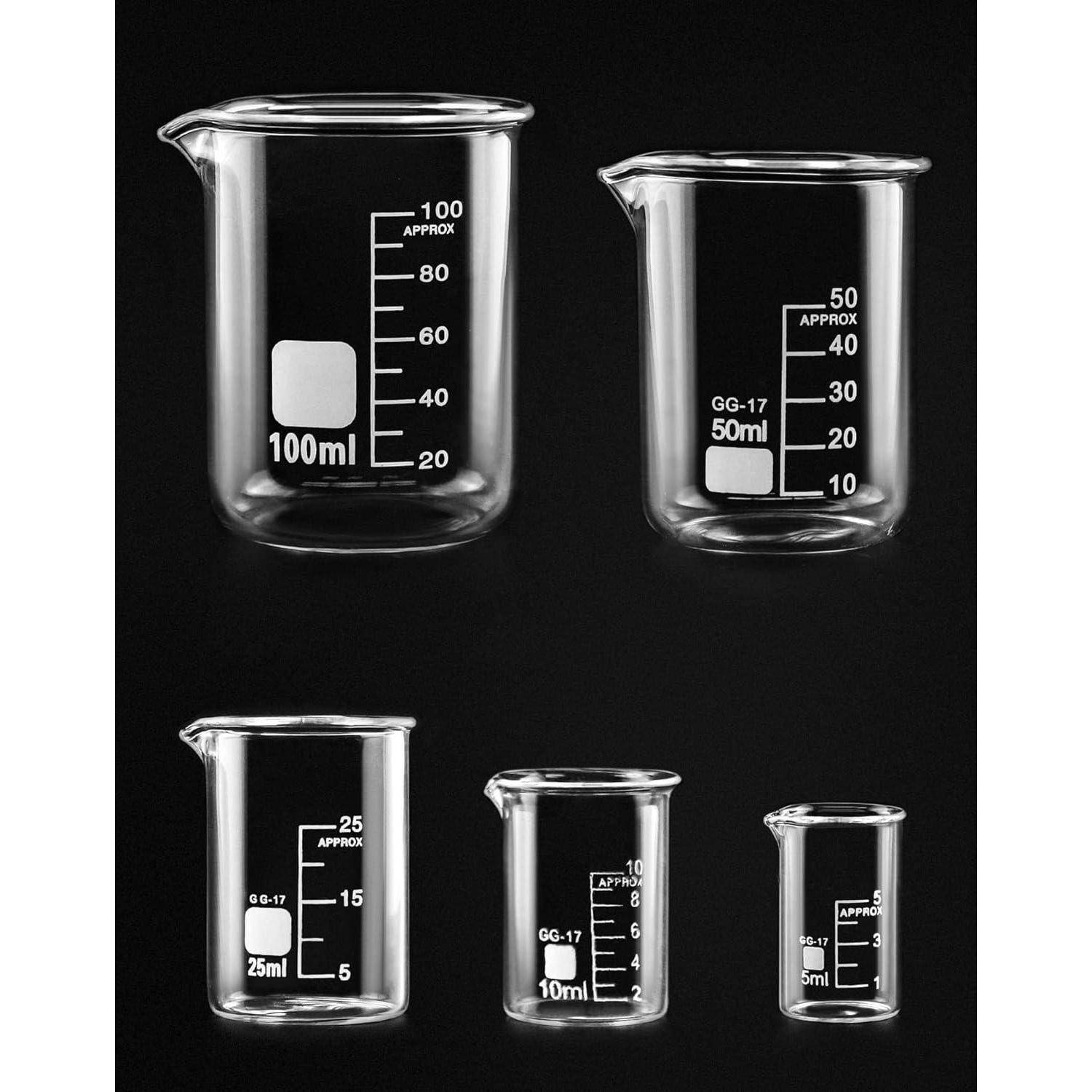Fünf transparente Glasbecher unterschiedlicher Größen mit Milliliter-Markierungen, gegen einen dunklen Hintergrund angeordnet.