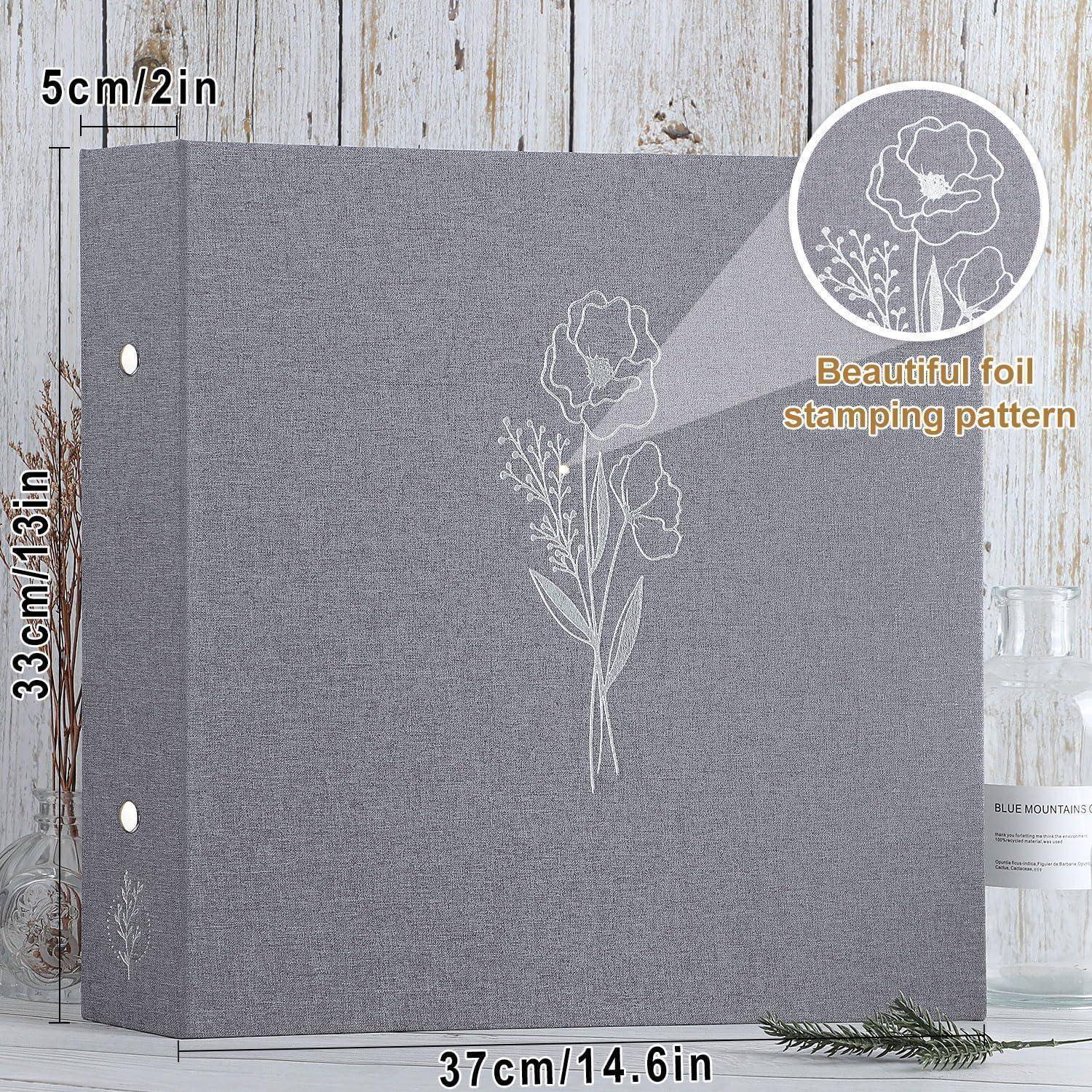 Großes graues Fotoalbum mit Blumenfolienprägung auf dem Einband, 37 cm breit, 33 cm hoch und 5 cm dick, aufrecht auf einer Holzoberfläche stehend.