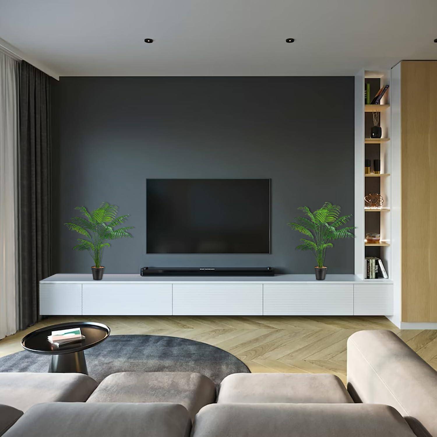 Moderner Wohnraum mit einer wandmontierten TV-Anlage, flankiert von zwei Topfpflanzen. Minimalistisches Design mit einer grauen Akzentwand und offenen Regalen.