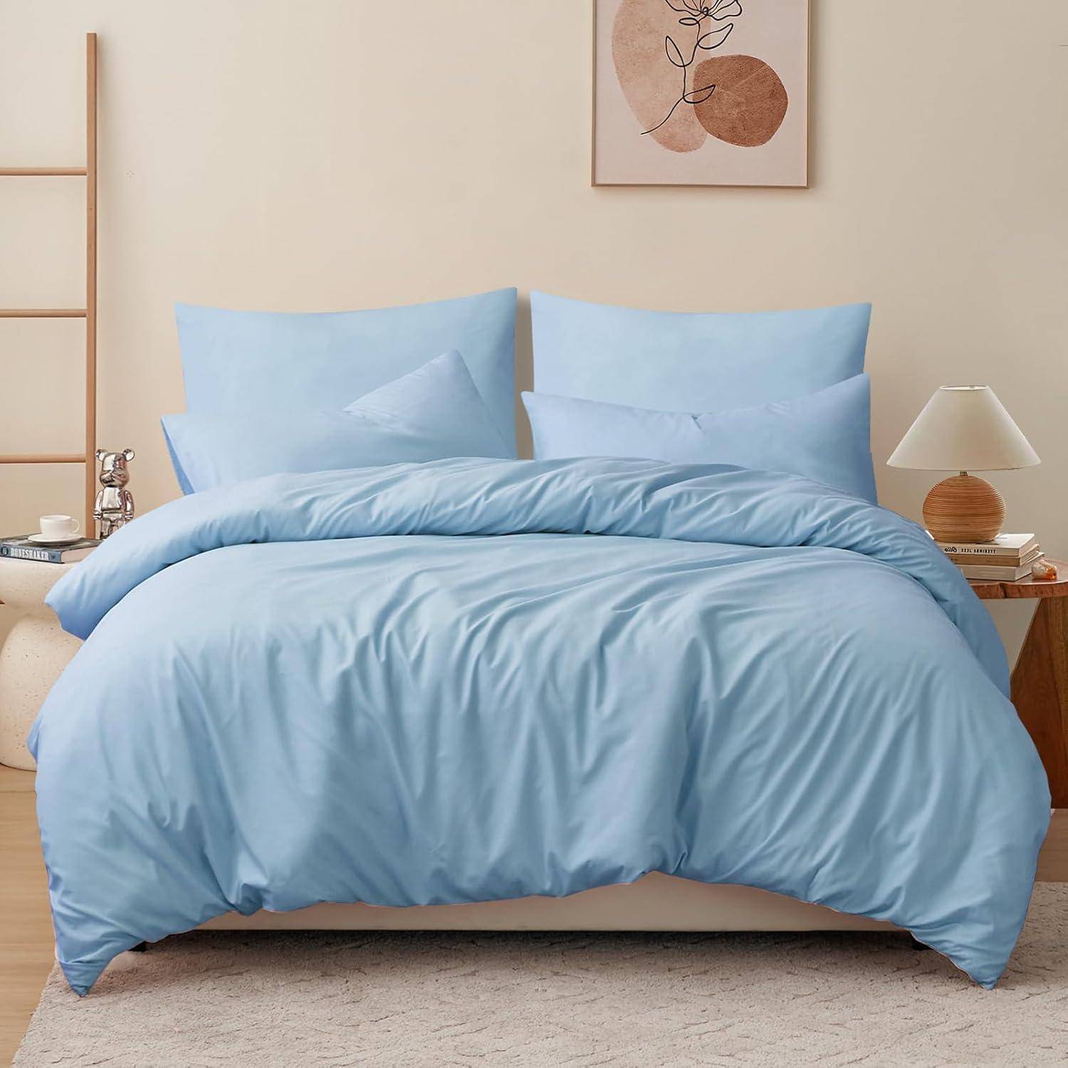 Ein ordentlich gemachtes Bett mit hellblauer Bettwäsche, zwei Kissen an einem Holzkopfteil und einem Nachttisch mit einer Lampe und Büchern in einem gemütlichen Schlafzimmer.