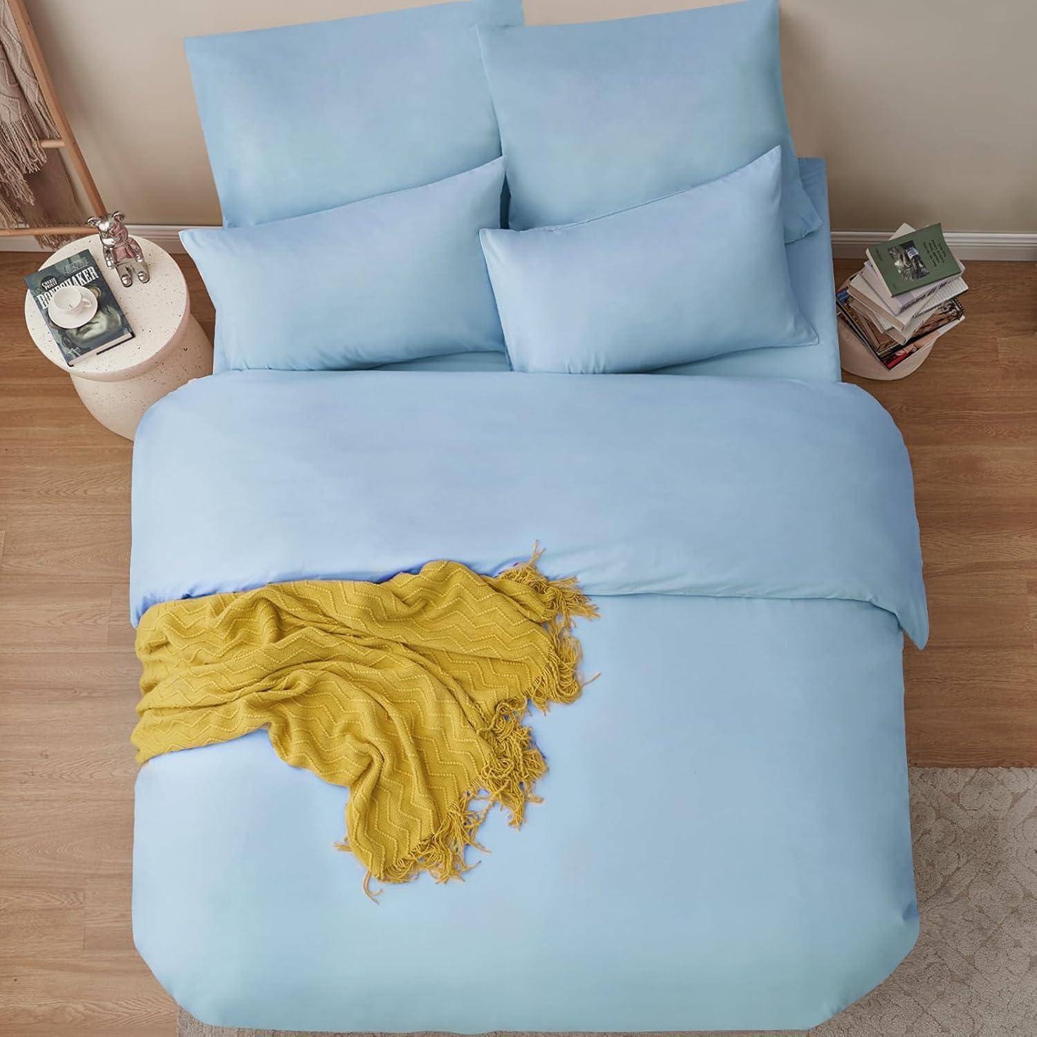 Ein sauber gemachtes Bett mit hellblauen Bettwäsche und Kissen, versehen mit einer gelben Decke, die darüber drapiert ist, in einer gemütlichen Schlafzimmeratmosphäre.