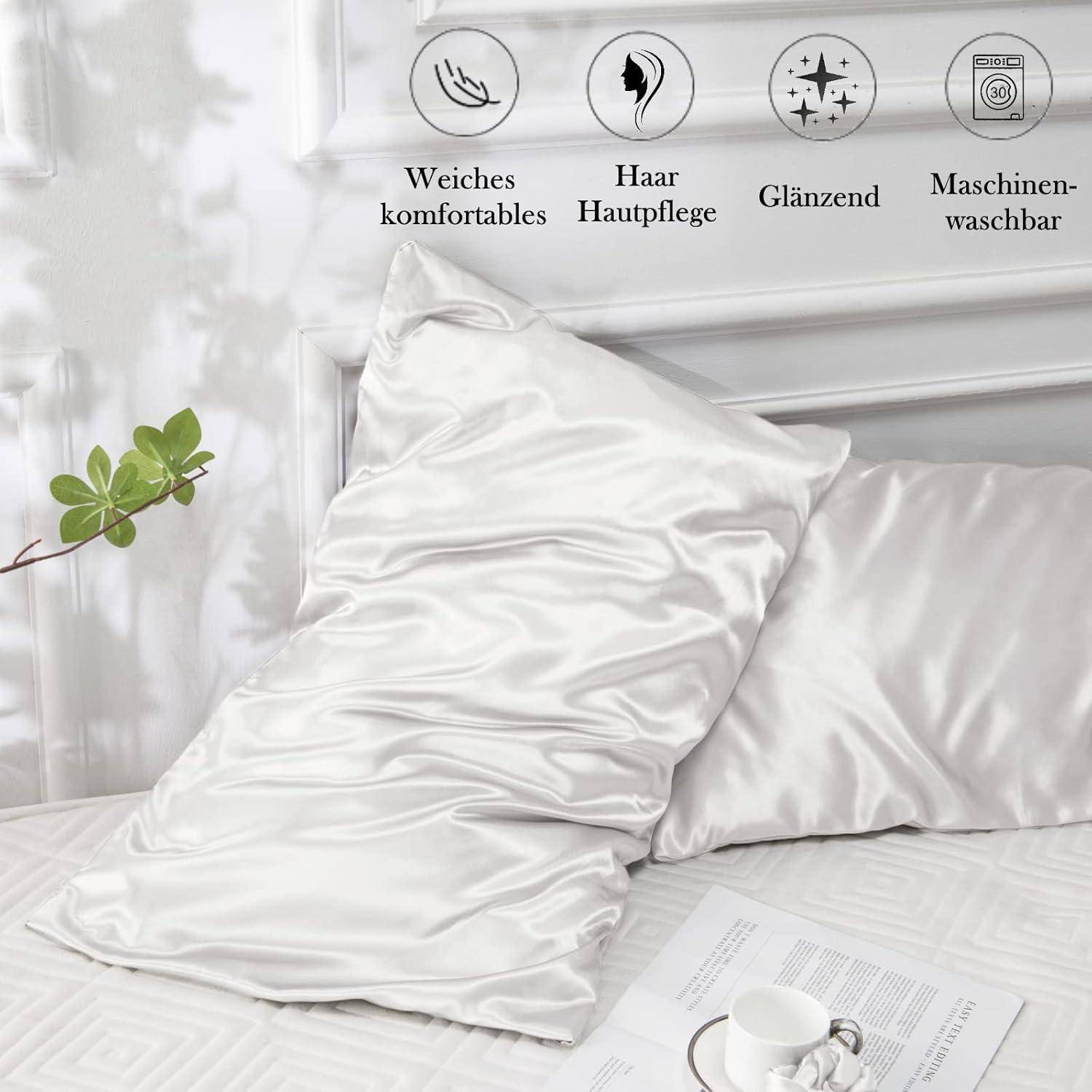 Weiße Seidenkissenbezüge auf einem Bett mit Pflanze, Büchern und einer Tasse in der Nähe. Über dem Bild befinden sich Icons, die Weichheit, Haarpflege, Glanz und Maschinenwäsche hervorheben.