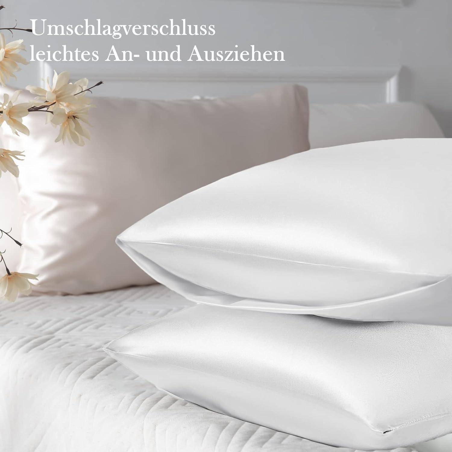 Weiße Kissenbezüge auf einem Bett, mit einer gesteppten Tagesdecke und dekorativen Blumen im Hintergrund. Text auf Deutsch wirbt für einfaches An- und Ausziehen.