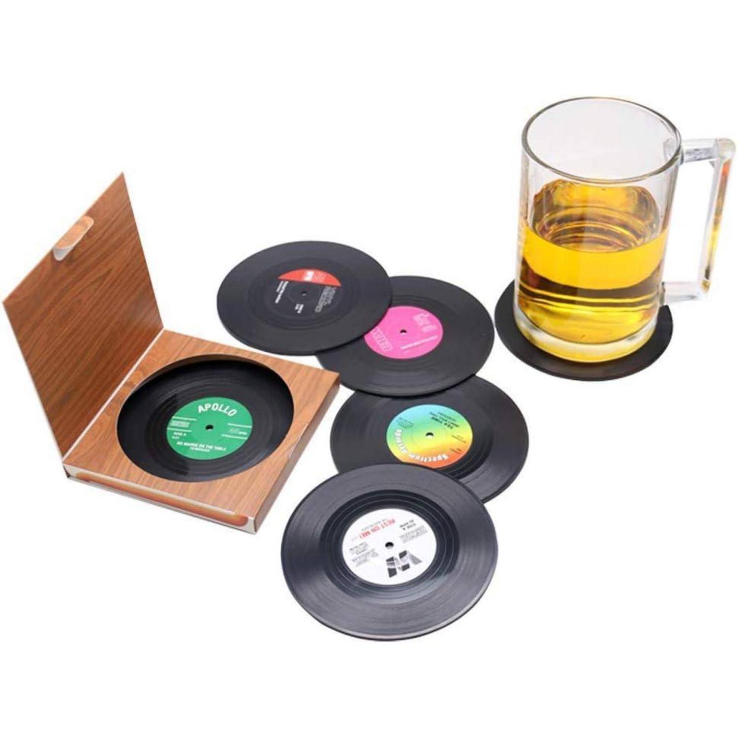 Vinyl-Untersetzer in verschiedenen Farben liegen neben einer Glastasse auf einem Untersetzer. Eine Holzbox enthält weitere Untersetzer.