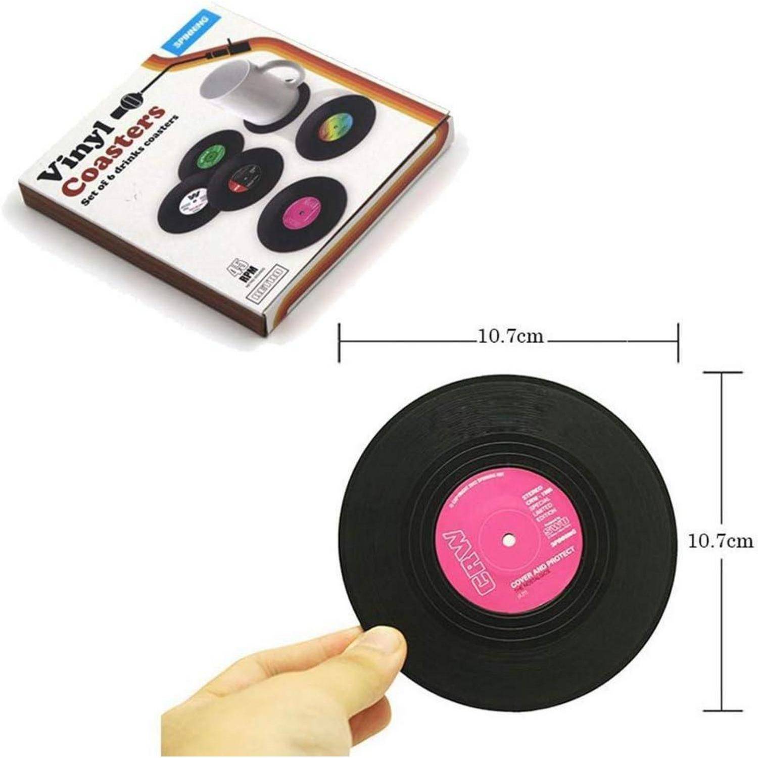 Eine Hand hält einen runden, schwarzen Vinyl-Untersetzer mit einem rosa Zentrum, der an eine Schallplatte erinnert. In der Verpackung daneben sind drei weitere Untersetzer mit farbigen Zentren zu sehen. Die Abmessungen werden mit 10,7 cm angegeben.