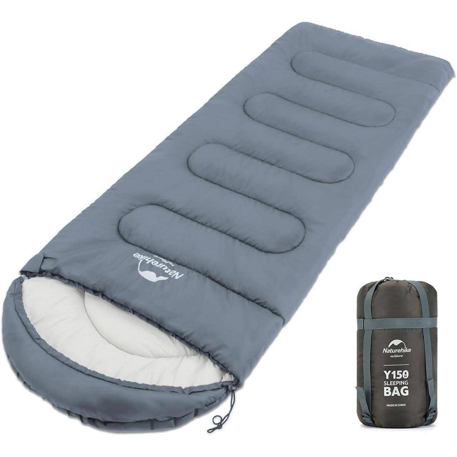 Ein grauer Schlafsack mit weichem, gepolstertem Design wird entfaltet dargestellt. Daneben ist derselbe Schlafsack in seinem Transportbeutel zusammengerollt.