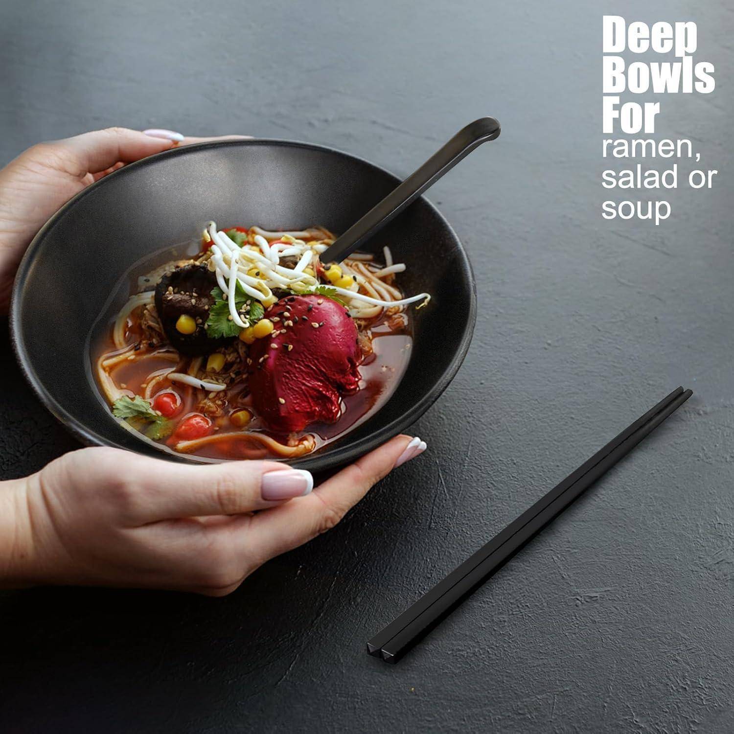 Zwei Hände halten eine schwarze Schüssel mit Ramen, mit Nudeln, Gemüse und einer roten Zutat, daneben schwarze Essstäbchen. Text lautet: 