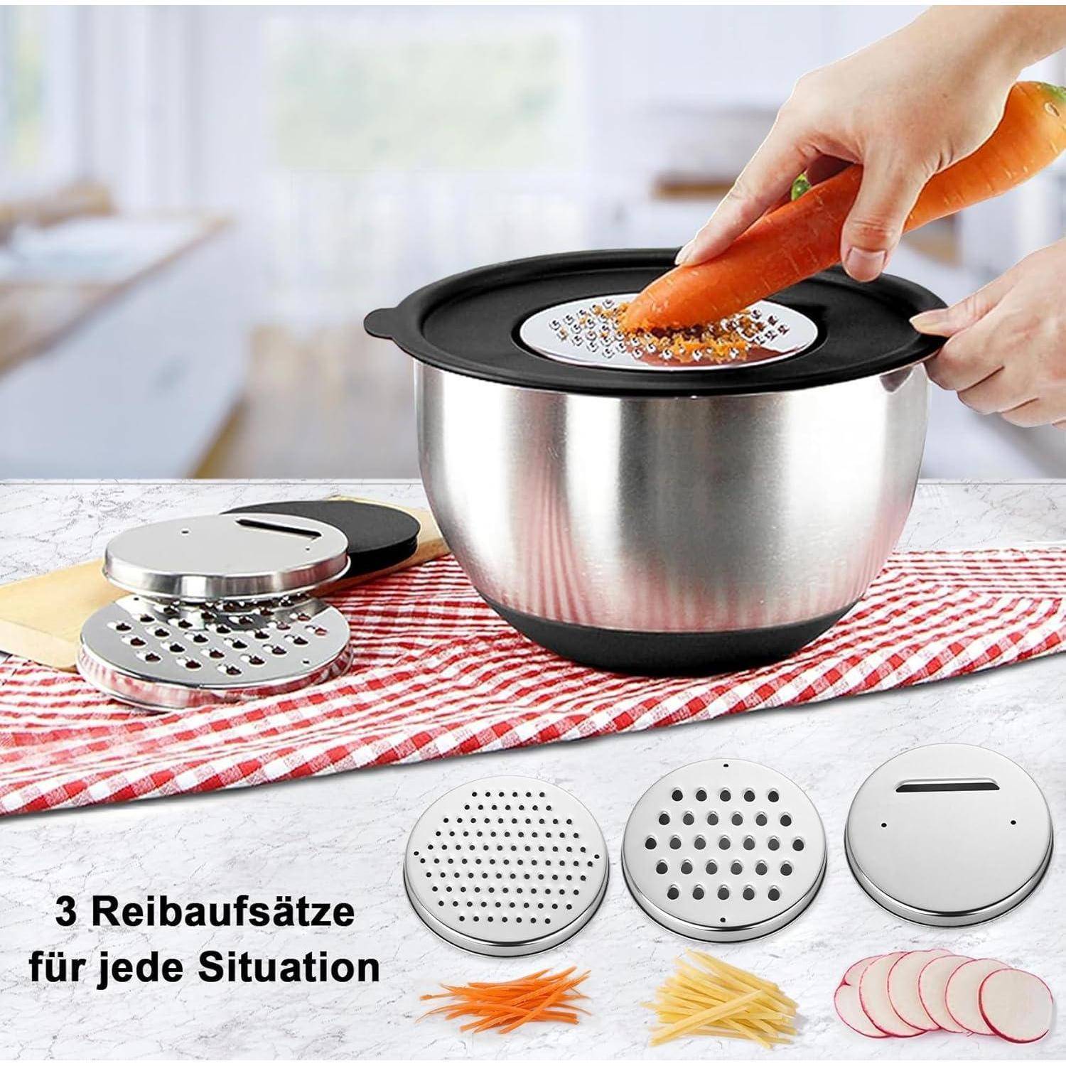 Eine Hand hobelt eine Karotte über eine Schüssel mit einem Deckel, der einen Reiberaufsatz enthält, umgeben von zusätzlichen Reiberaufsätzen und geriebenen Karotten.