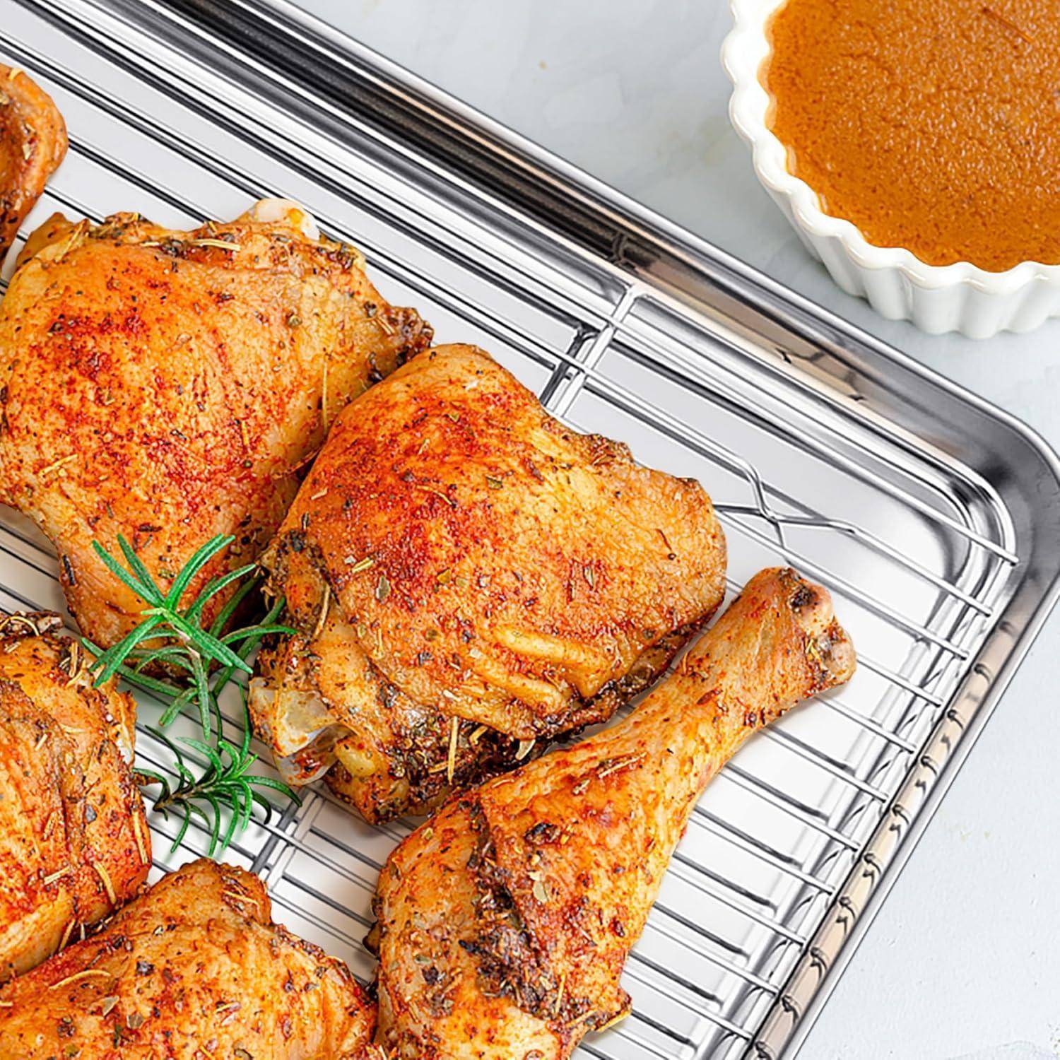 Gebratene Hühnerkeulen und -unterschenkel, mit Kräutern gewürzt, auf einem Drahtgitter angeordnet; eine kleine Schale mit Sauce ist in der Ecke sichtbar.