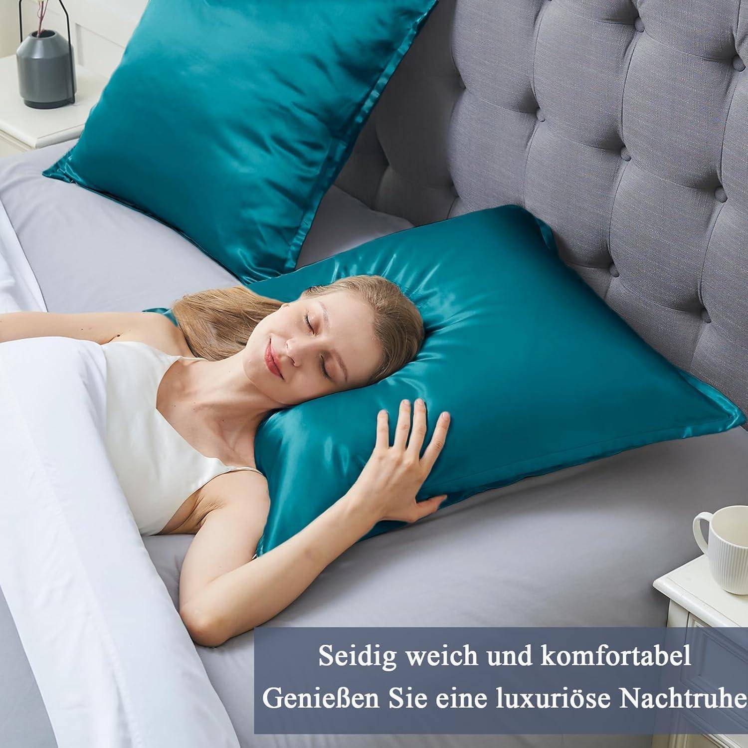 Eine Frau schläft friedlich auf einem Bett mit blauen Satin-Kissen und einer grauen Decke. Der Text lautet: „Seidig glatt und komfortabel. Genießen Sie eine luxuriöse Nachtruhe.