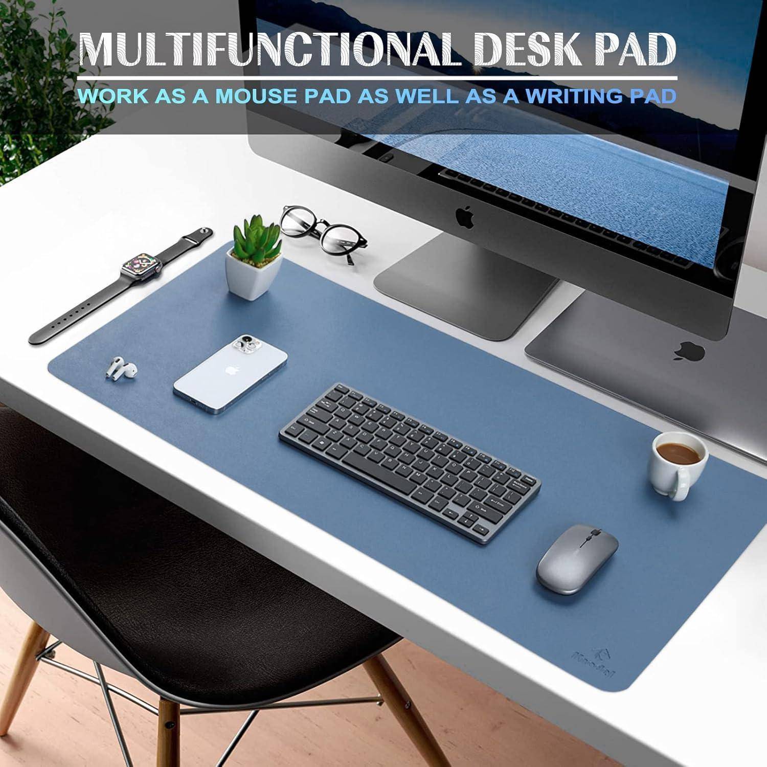 Eine moderne Büro-Schreibtischeinrichtung mit einer blauen multifunktionalen Schreibtischunterlage, Tastatur, Maus, Smartphone, Uhr, Pflanze, Brille und einem Computermonitor.