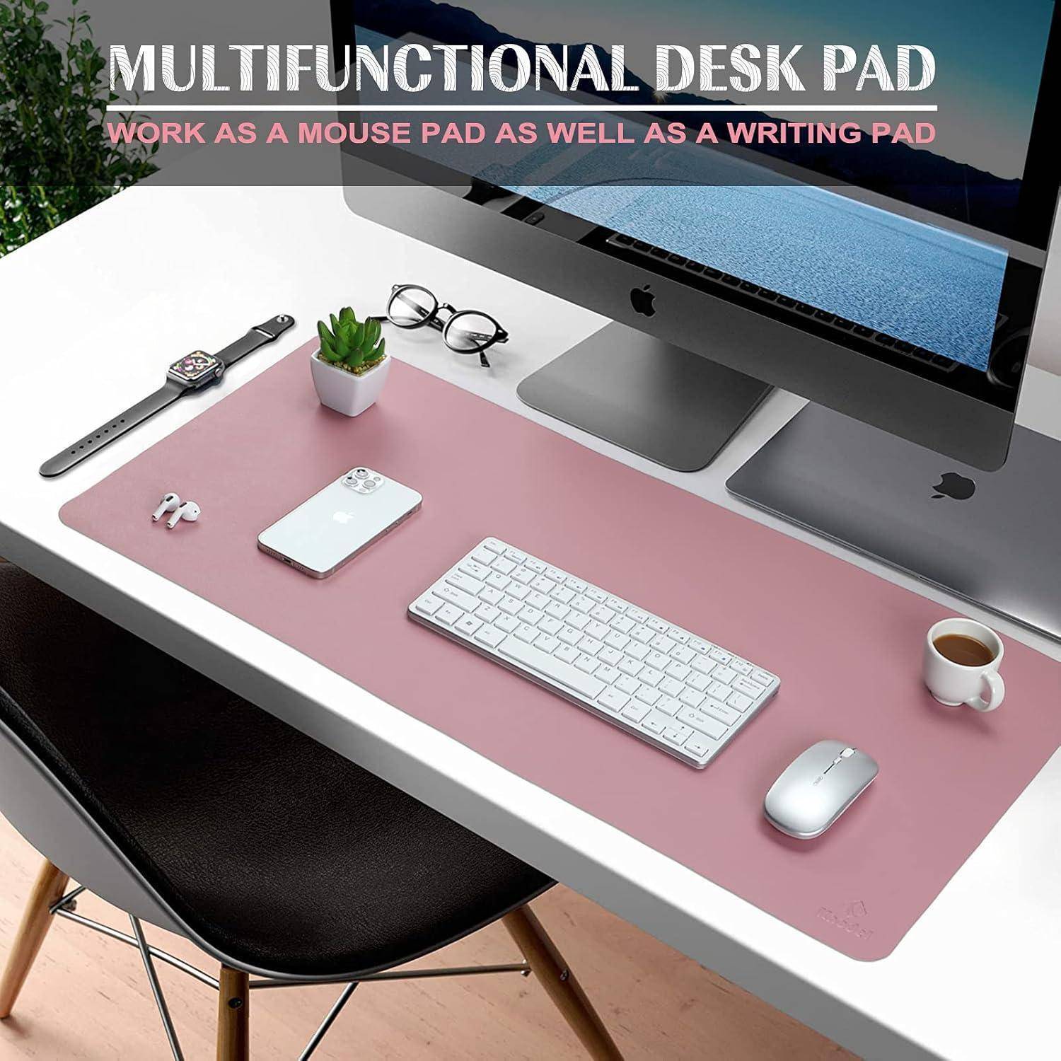 Ein aufgeräumter Arbeitsplatz mit einem großen rosa Schreibunterlage, die sowohl als Maus- als auch als Schreibunterlage dient, unter einem Computer, einer Tastatur, einem Telefon und einer Kaffeetasse.