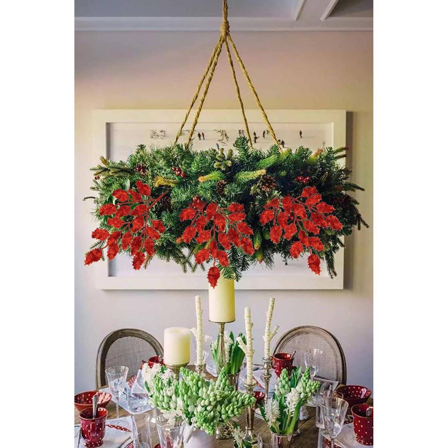 Ein Esstisch, der für einen festlichen Anlass gedeckt ist, mit einem hängenden Kranz aus roten und grünen Blättern, Kerzen und elegantem Geschirr.