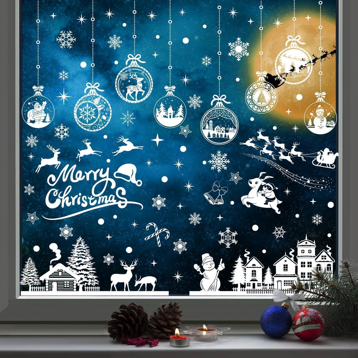 Eine festliche Schaufenstergestaltung zeigt einen 'Frohe Weihnachten'-Schriftzug, Santas Schlitten im Mondlicht, Christbaumschmuck und eine verschneite Dorfszene.