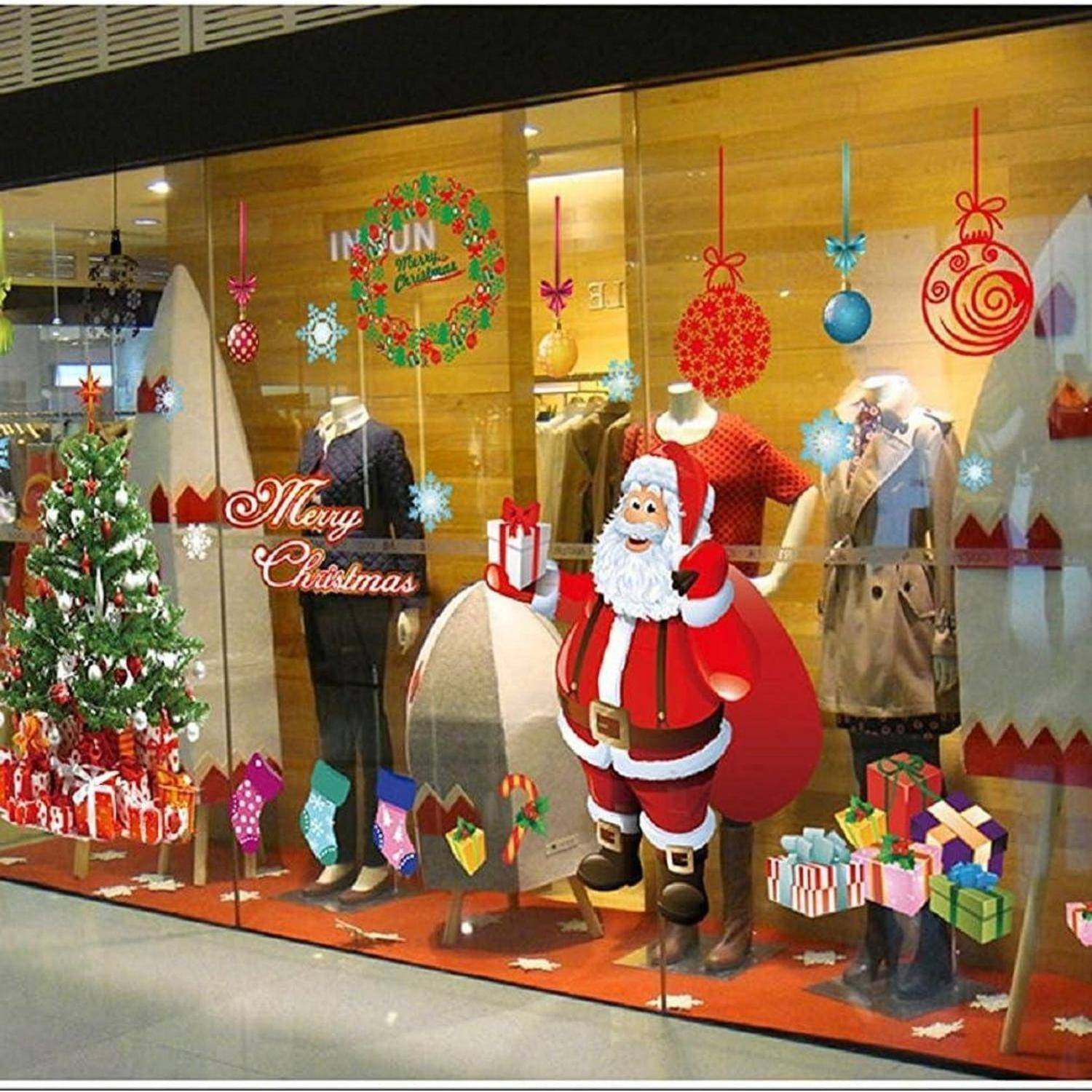 Schaufenster mit Schaufensterpuppen, die in Winterkleidung gekleidet sind, Weihnachtsdekoration einschließlich eines Baumes, einer Weihnachtsmannfigur, Geschenken und dem Text „Frohe Weihnachten