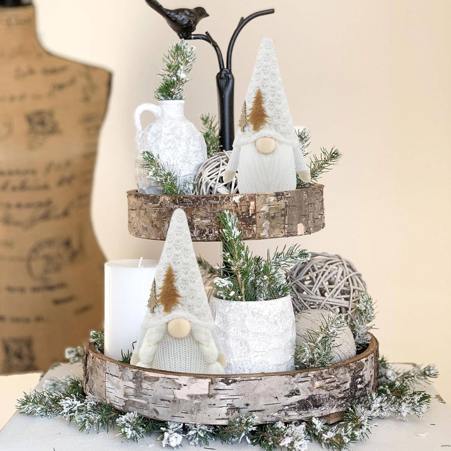 Weihnachtlich gestaltete Tischdekoration mit zwei Gnom-Figuren, Kerzen und dekorativen Vasen, die alle auf einem zweistufigen Holzständer angeordnet sind.