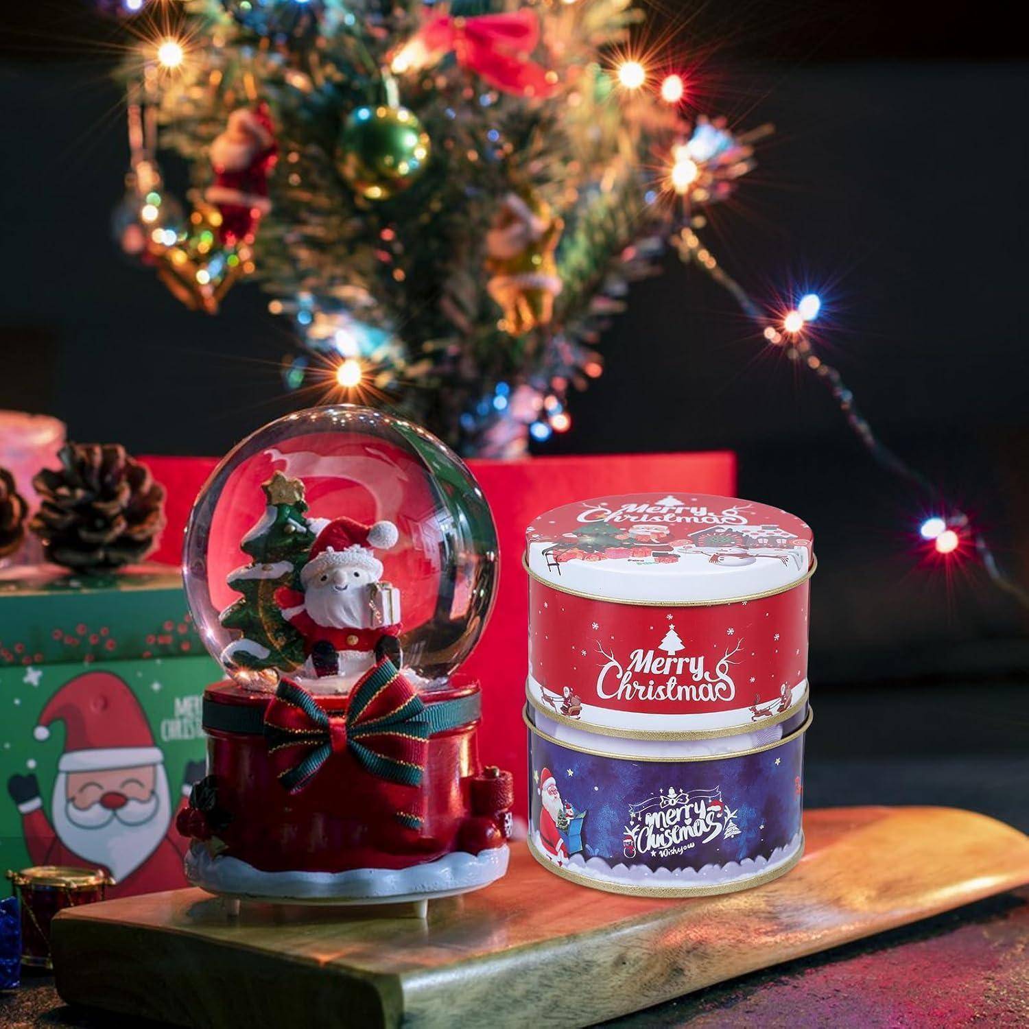 Weihnachtliche Szene mit einer Schneekugel, die ein Rentier zeigt, und zwei festlich beschrifteten Blechdosen mit der Aufschrift 