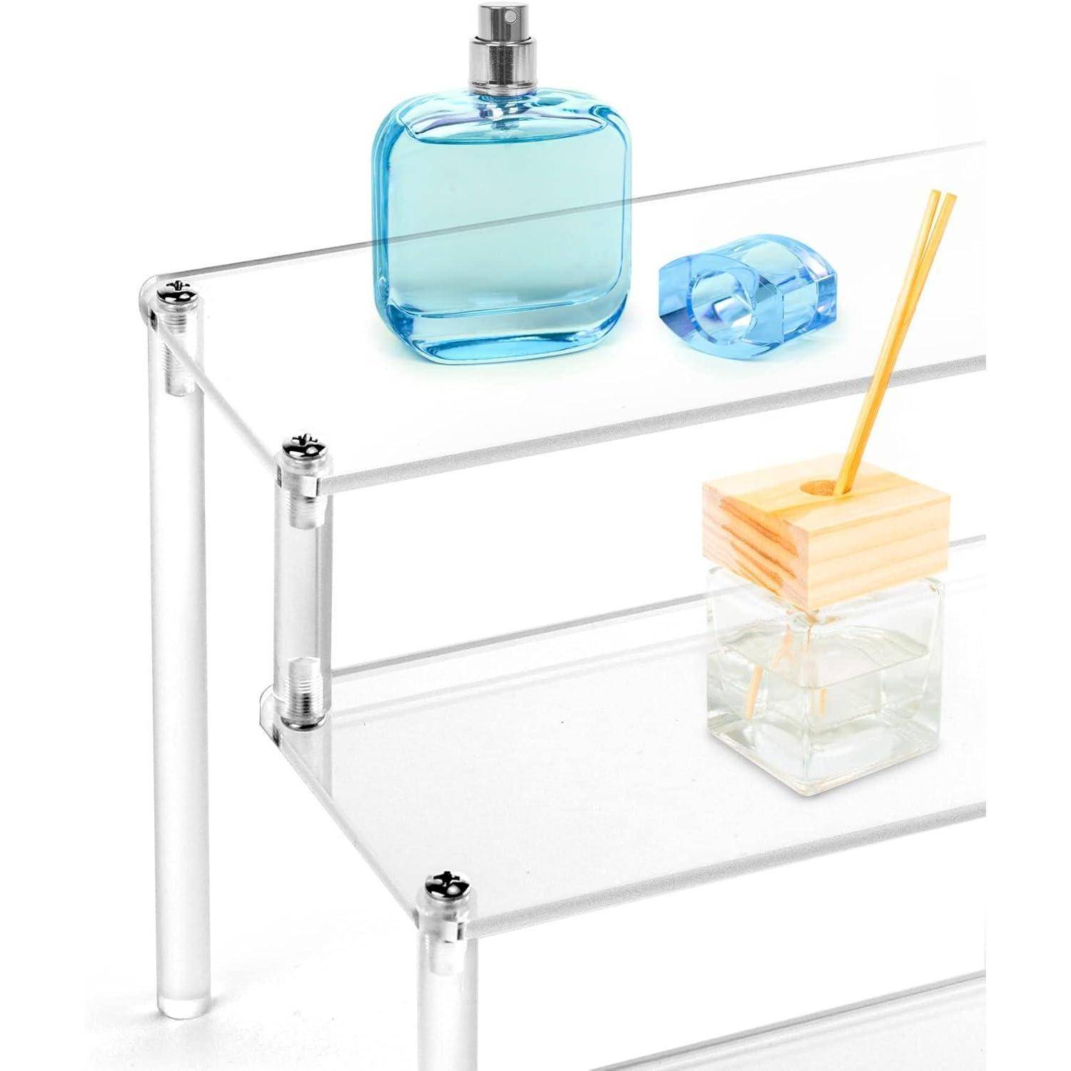 Zweistufiges Glasregal mit einer blauen Parfümflasche, einem blauen Klebebandabroller und einem Glasreed-Diffuser mit Holzdeckel auf dem oberen Regal.